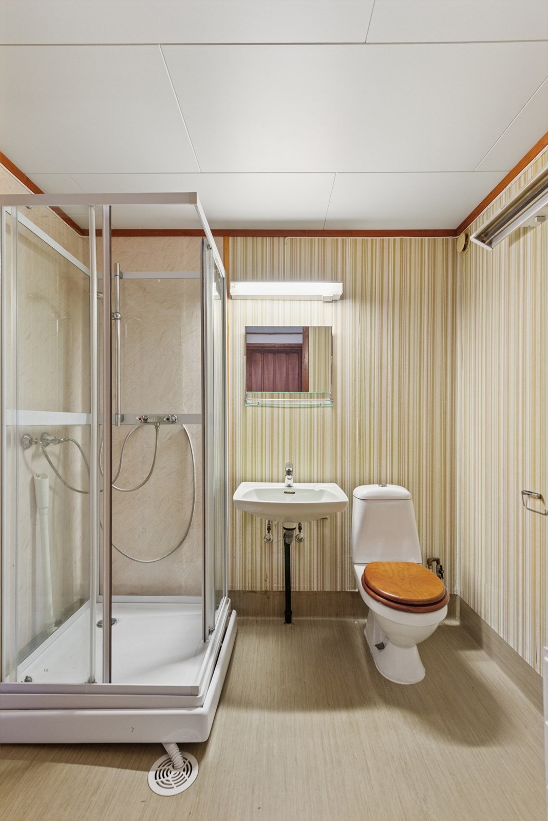 Badet i hybelen består av speil, servant, gulvmontert toalett, dusjkabinett og opplegg for vaskemaskin. Galleribilde