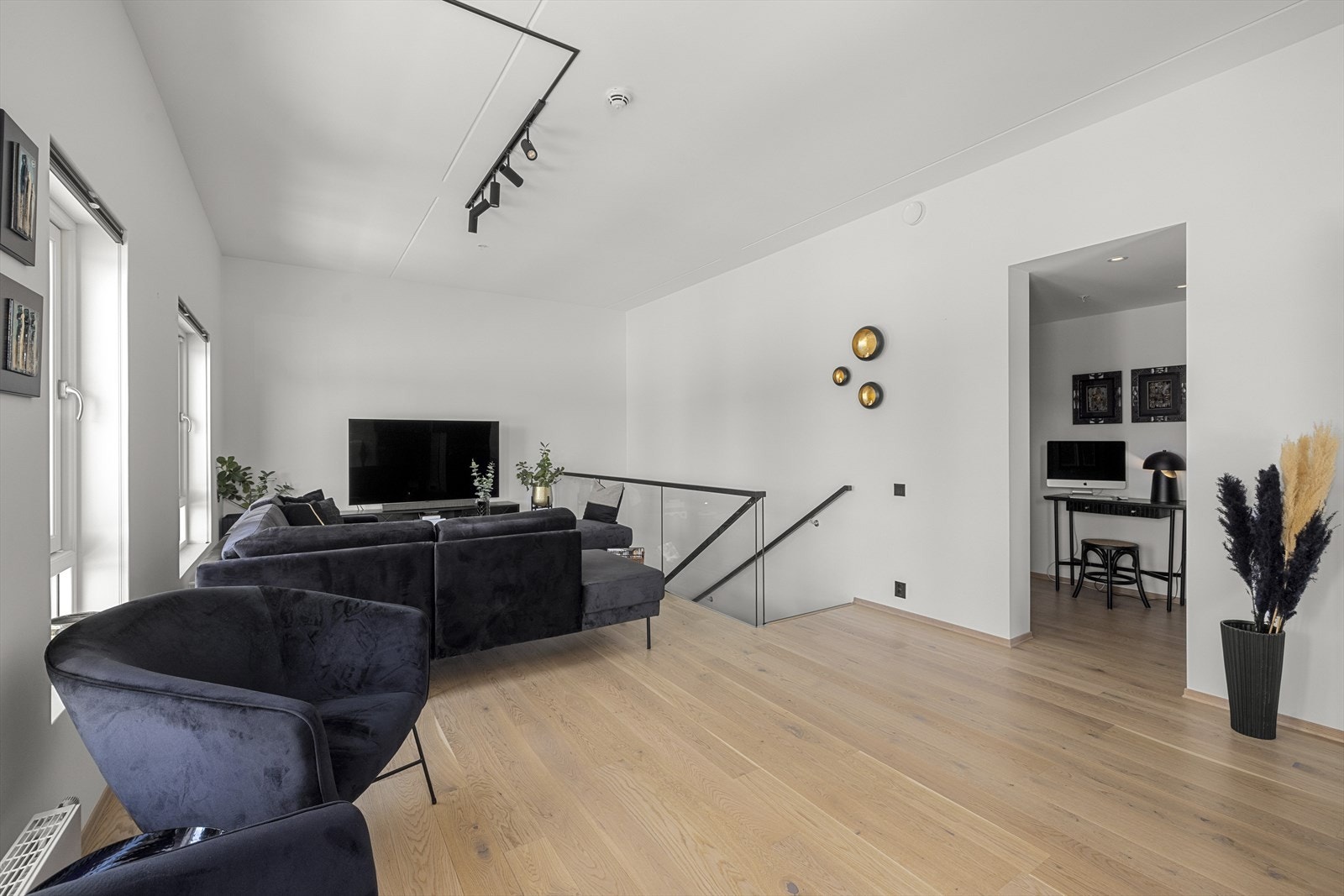 I boligens 2.etasje kommer man opp til en lun og romslig stue med god takhøyde og plass til stor sofagruppe Galleribilde