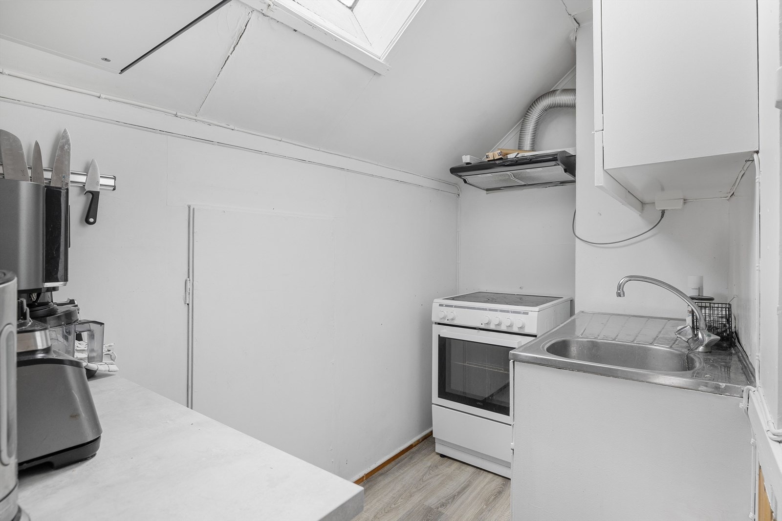 Kjøkken i hybelleiligheten. Innredningen har glatte fronter, laminert benkeplate og benkebeslag med nedfelt oppvaskkum. Galleribilde