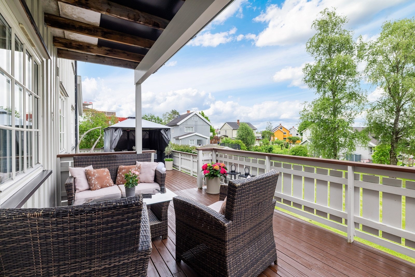 Terrassen er delvis overbygget, har terrassebord på gulv og malt rekkverk av tre. Galleribilde
