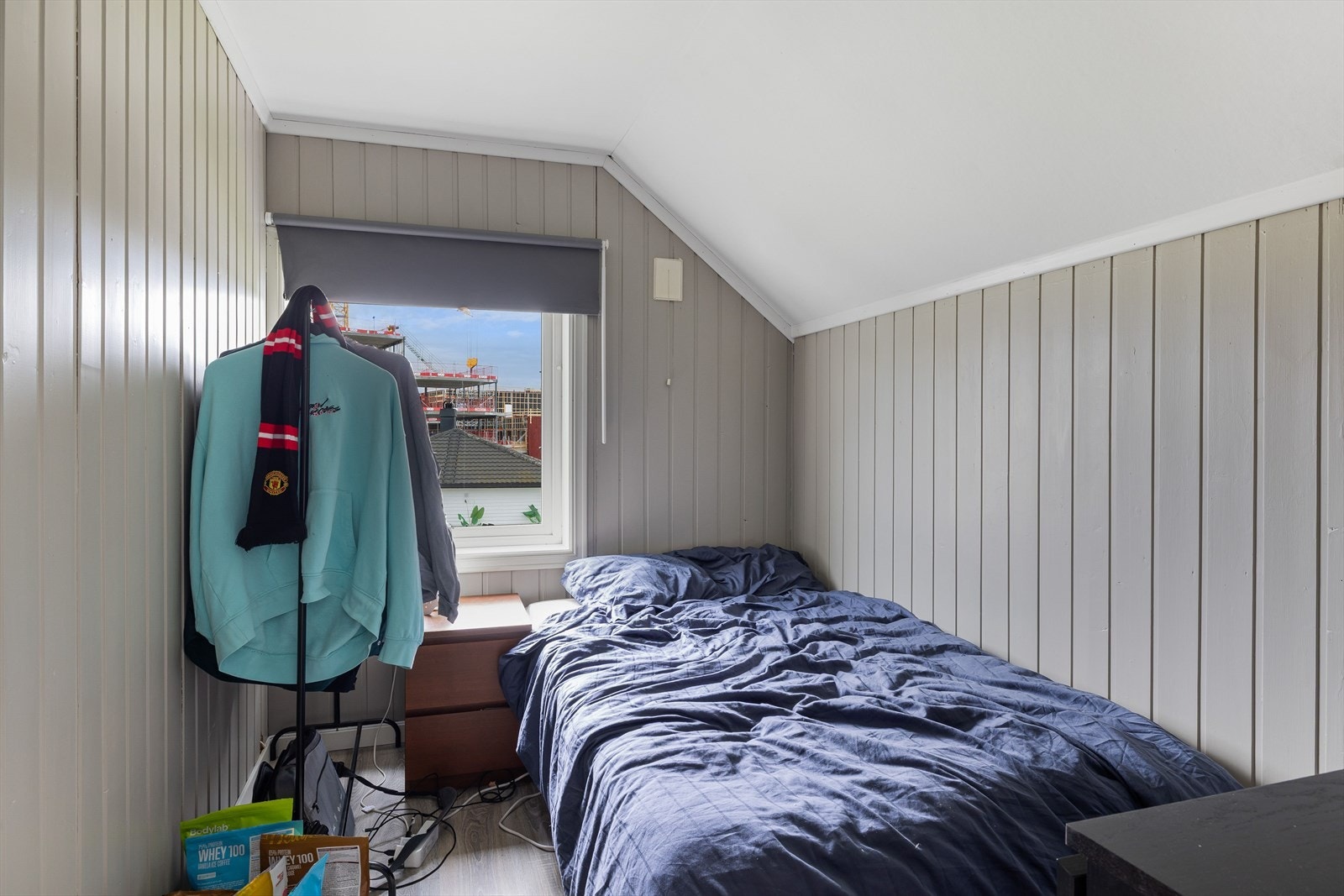 Soverommet i hybelleiligheten har enstavs laminat på gulv og panel på veggene malt i en fin farge. Det er montert brannstige utenfor vinduet. Galleribilde