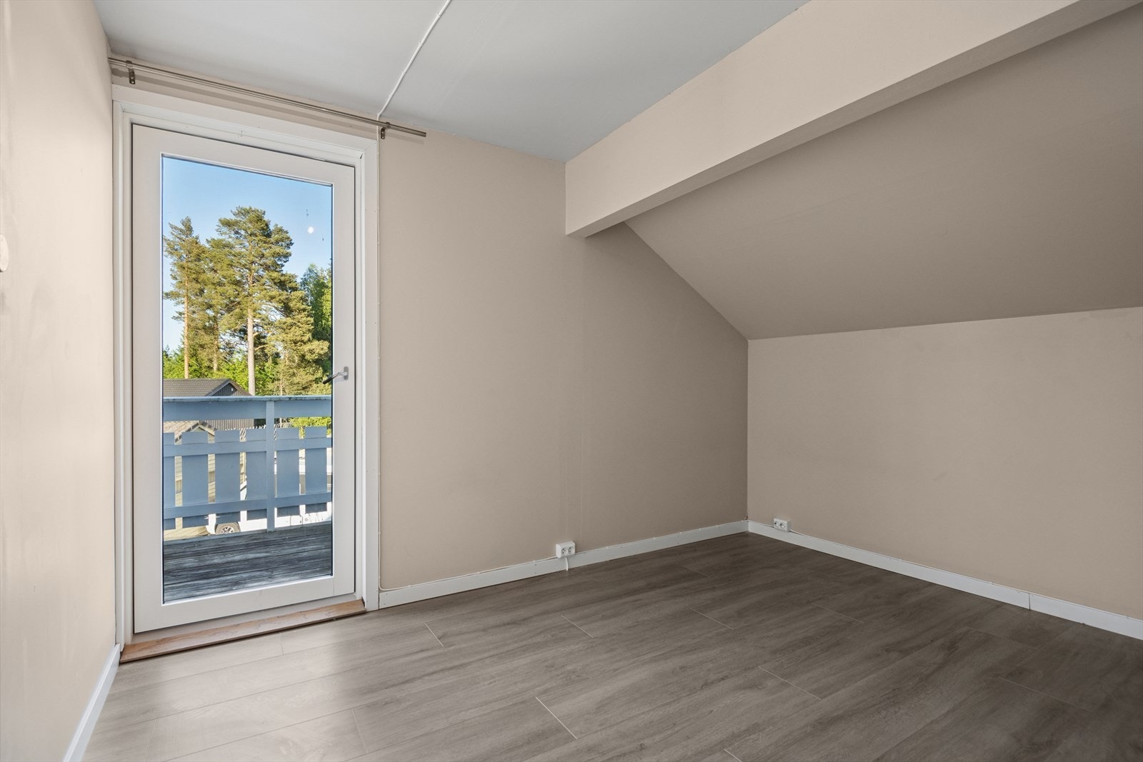 Soverom med utgang til balkong - et lyst rom med skråtak og fin utsikt, perfekt som hovedsoverom eller ungdomsrom. Galleribilde