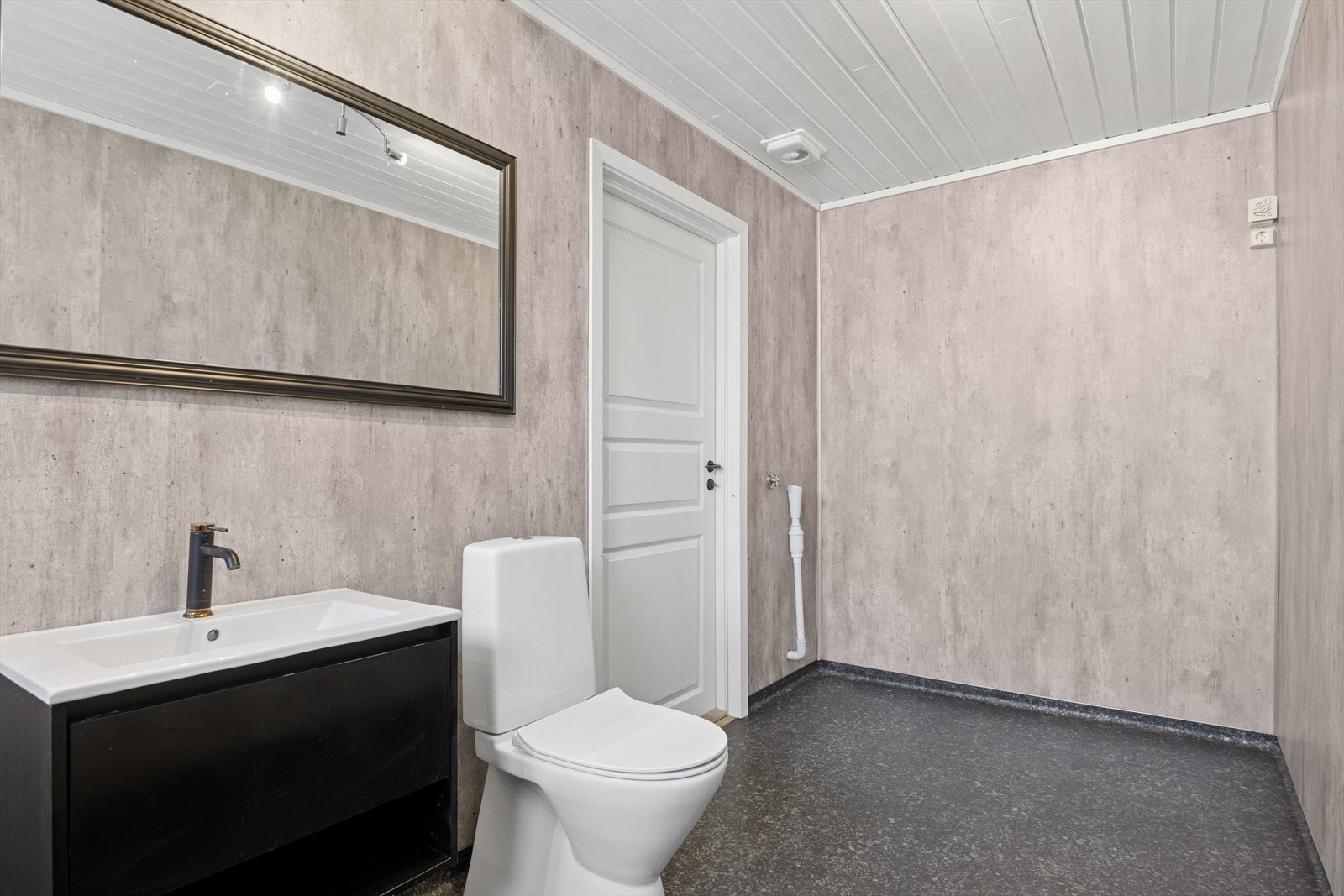 Badet er innredet med servantmøbel, speil, gulvmontert toalett og opplegg for vaskemaskin - alt i en romslig og funksjonell planløsning. Galleribilde