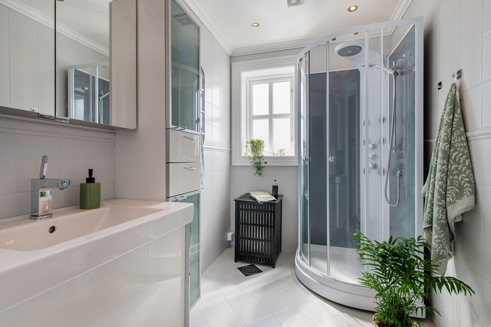 Badet er innredet med malte, lysegrå vegg- og gulvfliser. Downlights er installert i taket, og badet har varmekabler, vegghengt toalett og et dusjkabinett med regnfallsdusj. Galleribilde