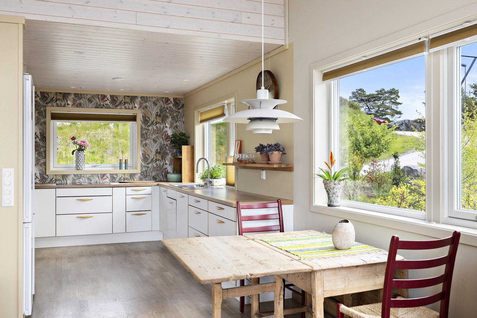 Kjøkkeninnredningen er stilren med slette hvite fronter og laminert benkeplate Galleribilde