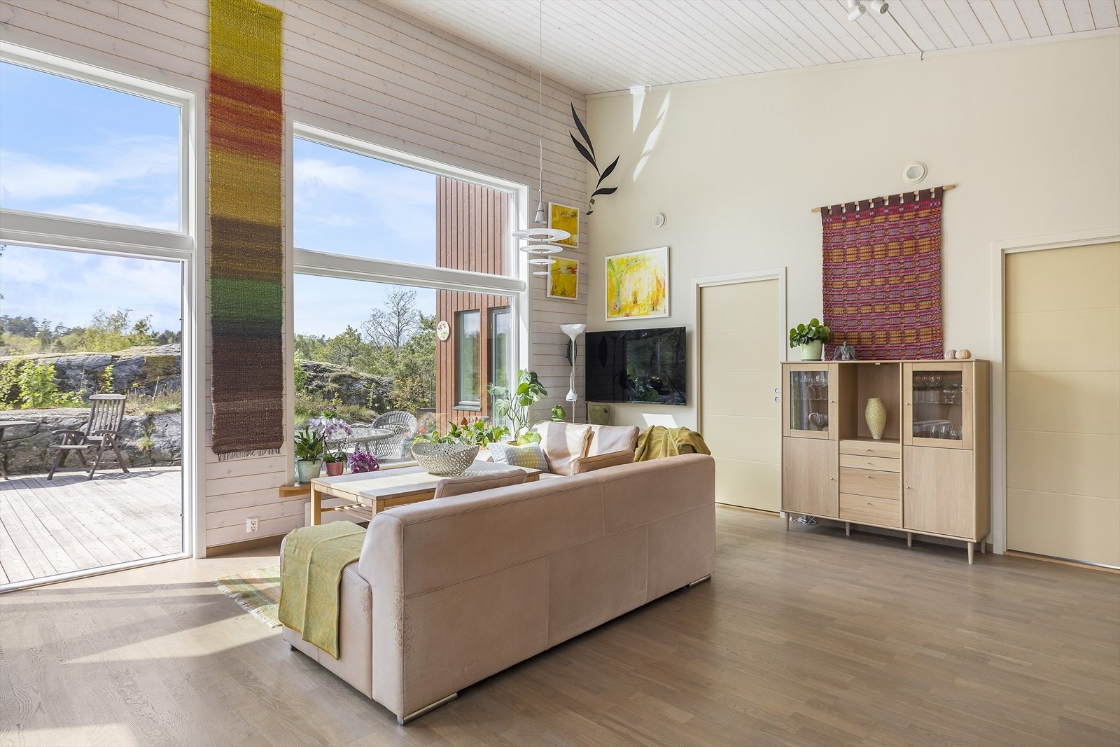 Store vinduer og verandaskyvedør i front gir godt med lys inn og utsyn til terrassen og naturområdene rundt Galleribilde