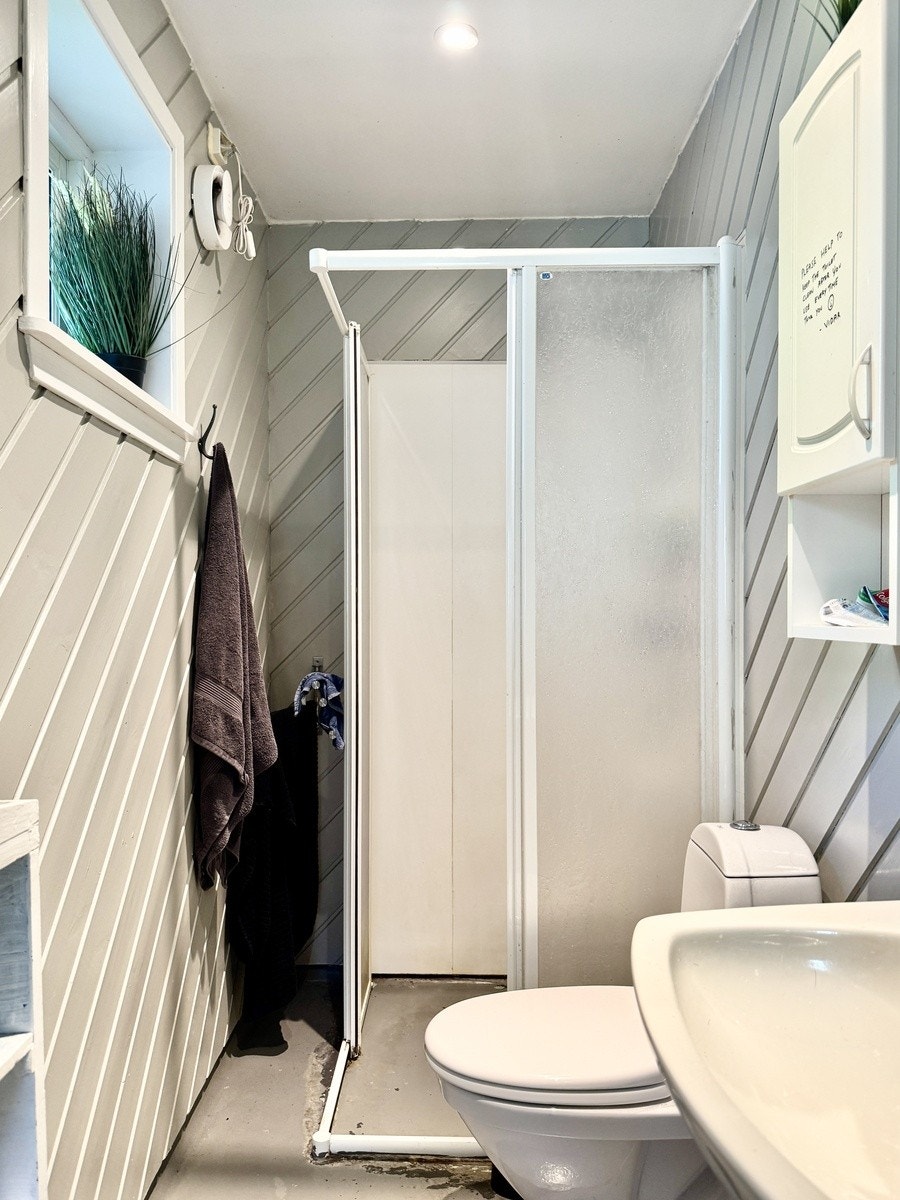 Lite dusjbad nede. Enkelt funksjonelt bad med dusj og toalett. Galleribilde