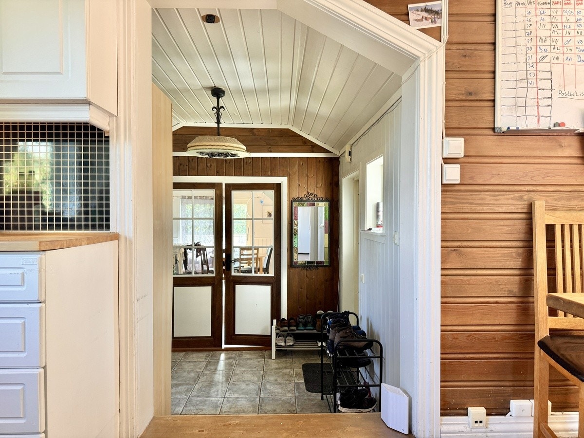 Fra kjøkken, kort trapp ned til hall med utgang både til atrium og til hagen, dør til lite dusjbad, og dører inn i stor stue med utgang terrasse. Galleribilde