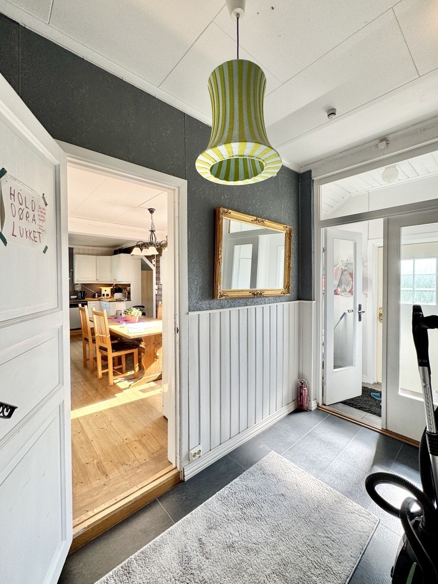 1. etg. Vindfang og ene inngangsdøren til høyre, kjøkken til venstre. Tatt fra trapp ned til kjelleren. Trapp opp til andre etasje er ikke med i bildet. Galleribilde