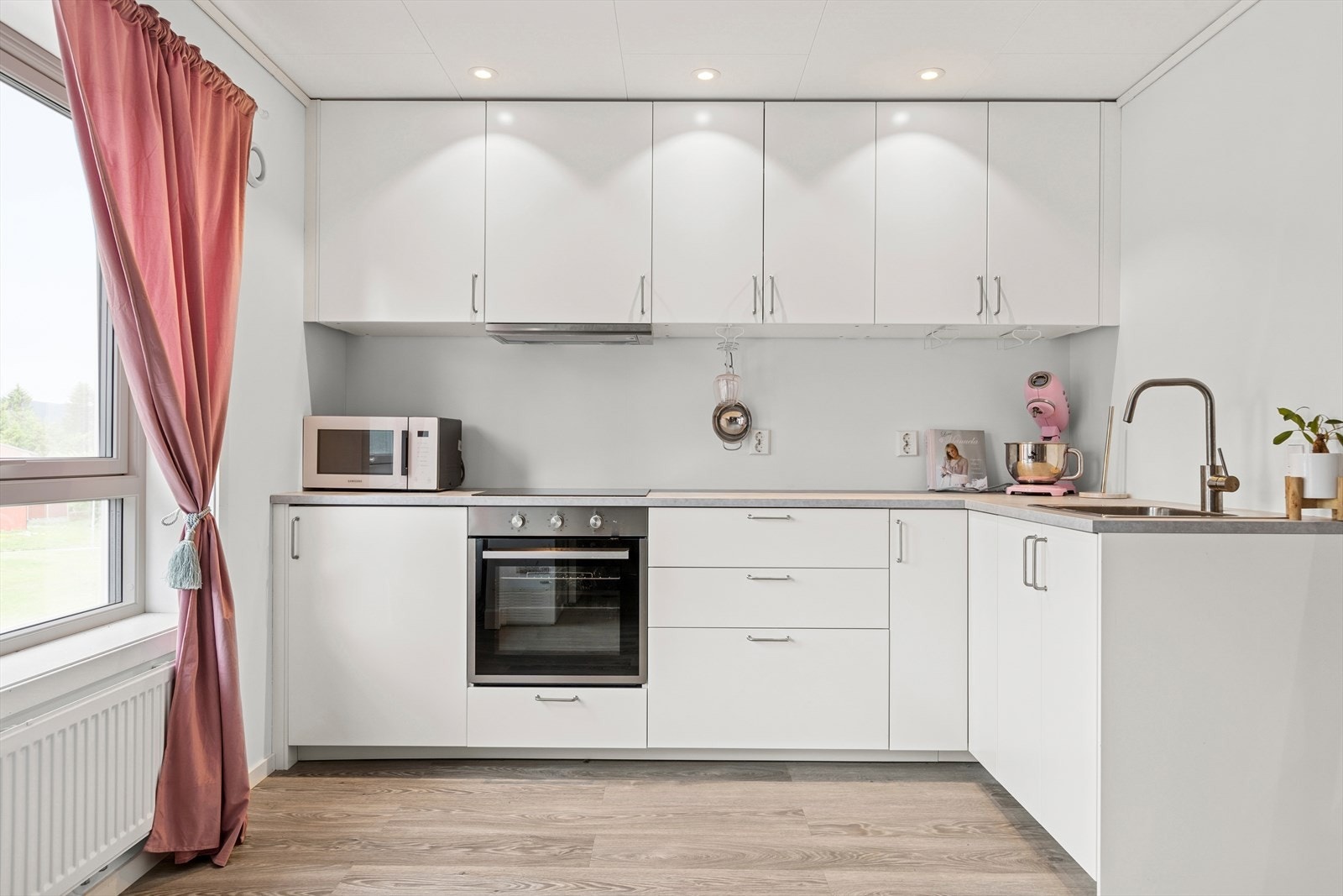 Oppusset med spotter i taket, nytt gulv og nye veggplater - oppusset i 2022 av Bygg Design. Hvitevarer med platetopp, stekeovn og ventilator. Det er kun etablert komfyrvakt over stekesonen. Galleribilde