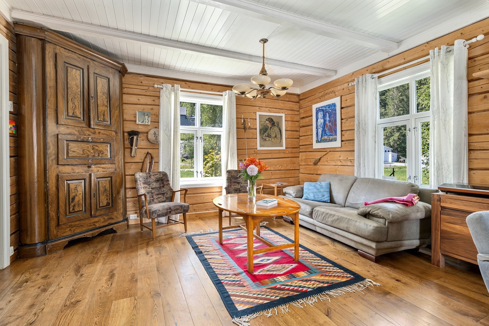 Pen stue med eksponerte tømmervegger som står i stil med laminatgulvet Galleribilde