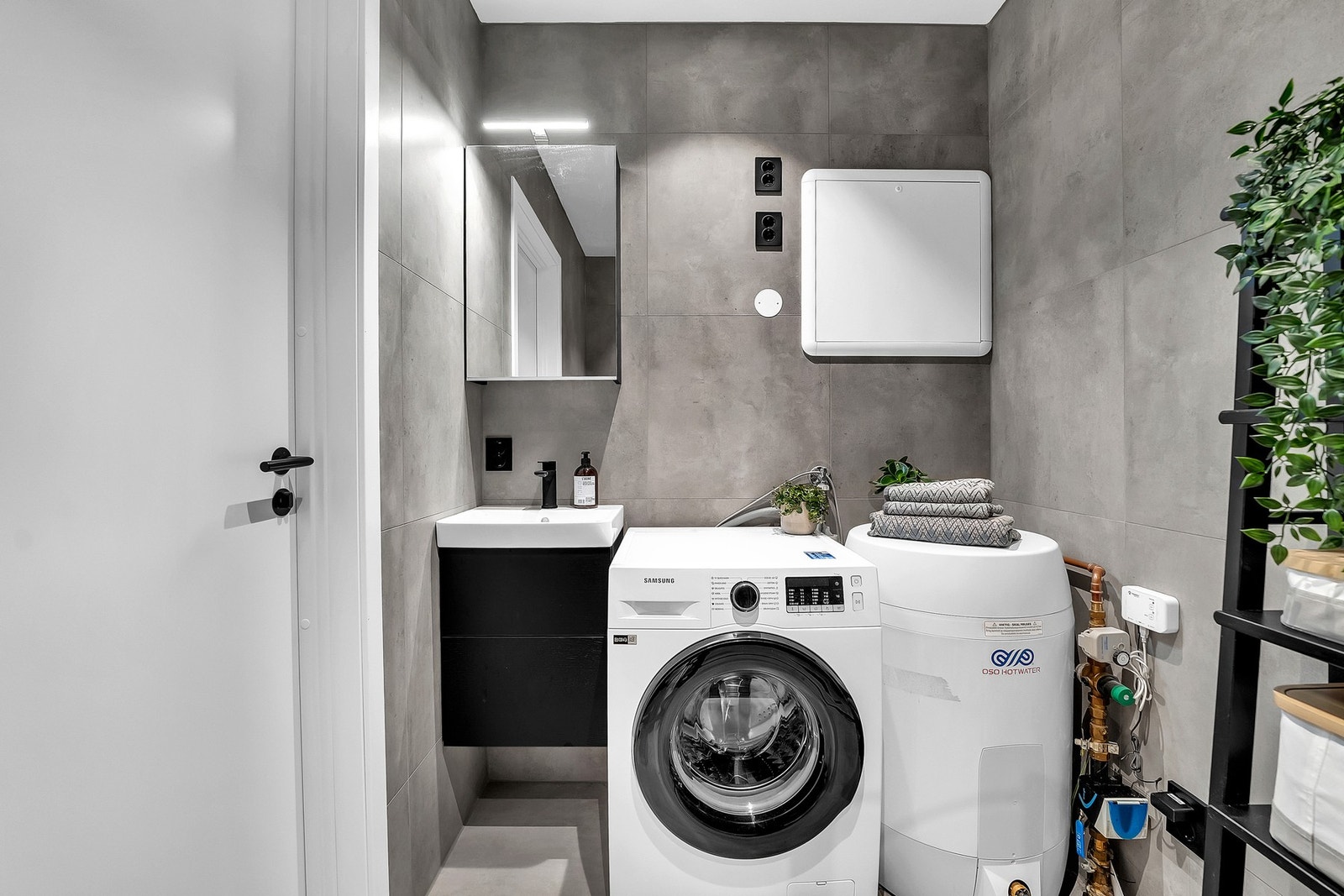 Sort vegghengt servantskap i glatt utførelse med push-open skuffer, med heldekkende servant med ett-greps armatur, dusjnisje med innfellbare glassdører og dusjarmatur tilkoblet hånddusj og regndusj, samt vegghengt toalett. Opplegg for vaskemaskin. Galleribilde