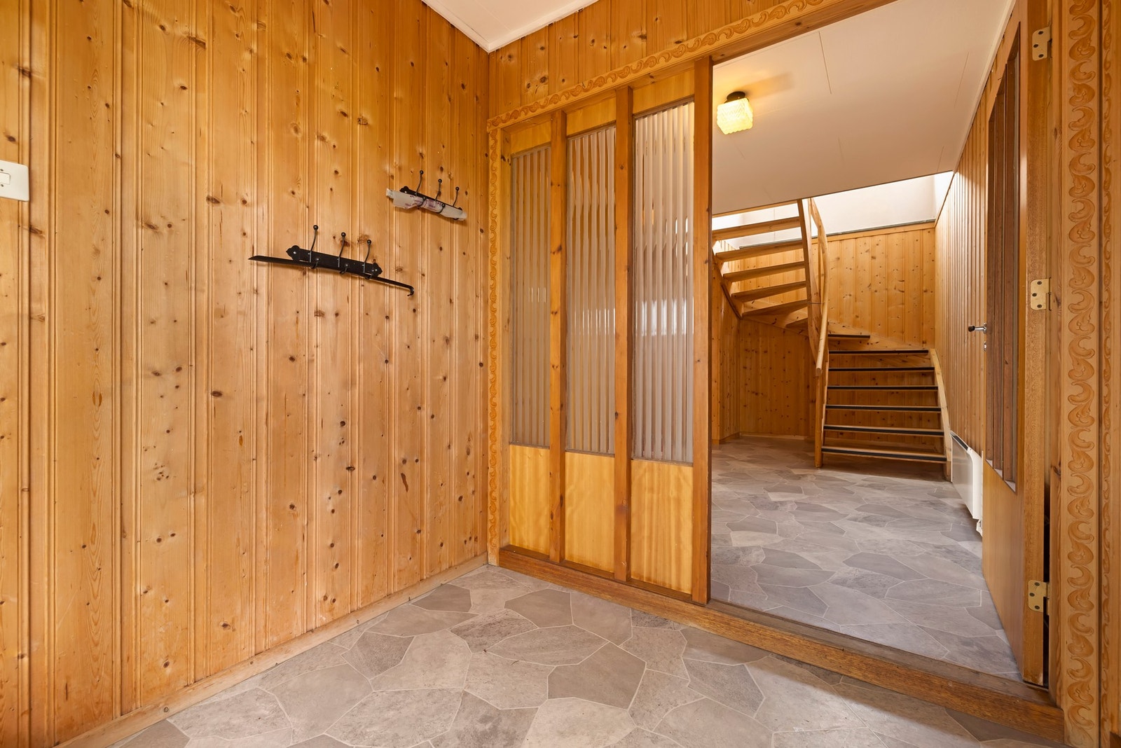 Romslig vindfang og gang med trapp opp til hovedetasjen samt inngang til sokkelleiligheten. Galleribilde