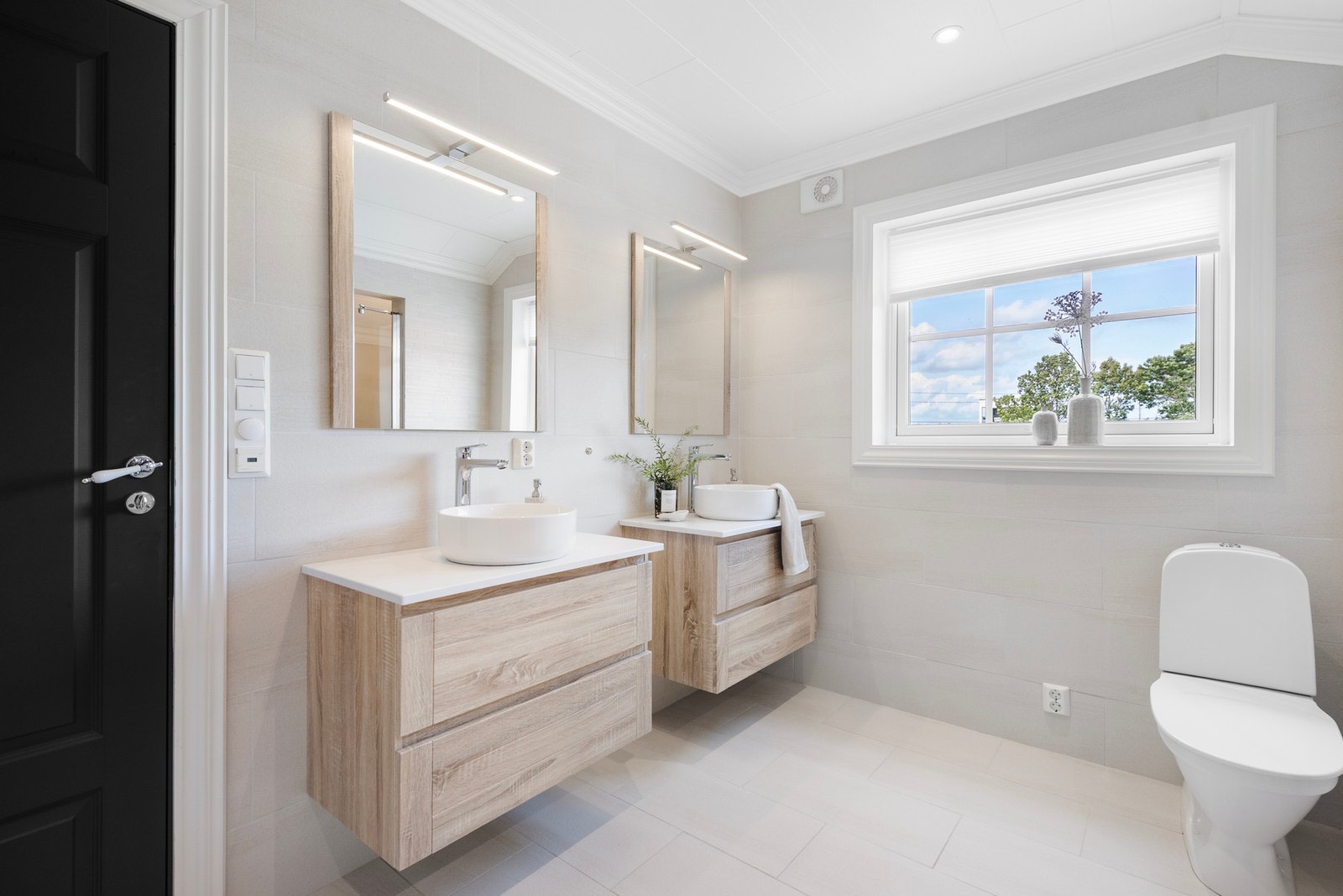 Lekkert flislagt badeværelse i varme toner, praktisk plassert rett ved entréen Galleribilde