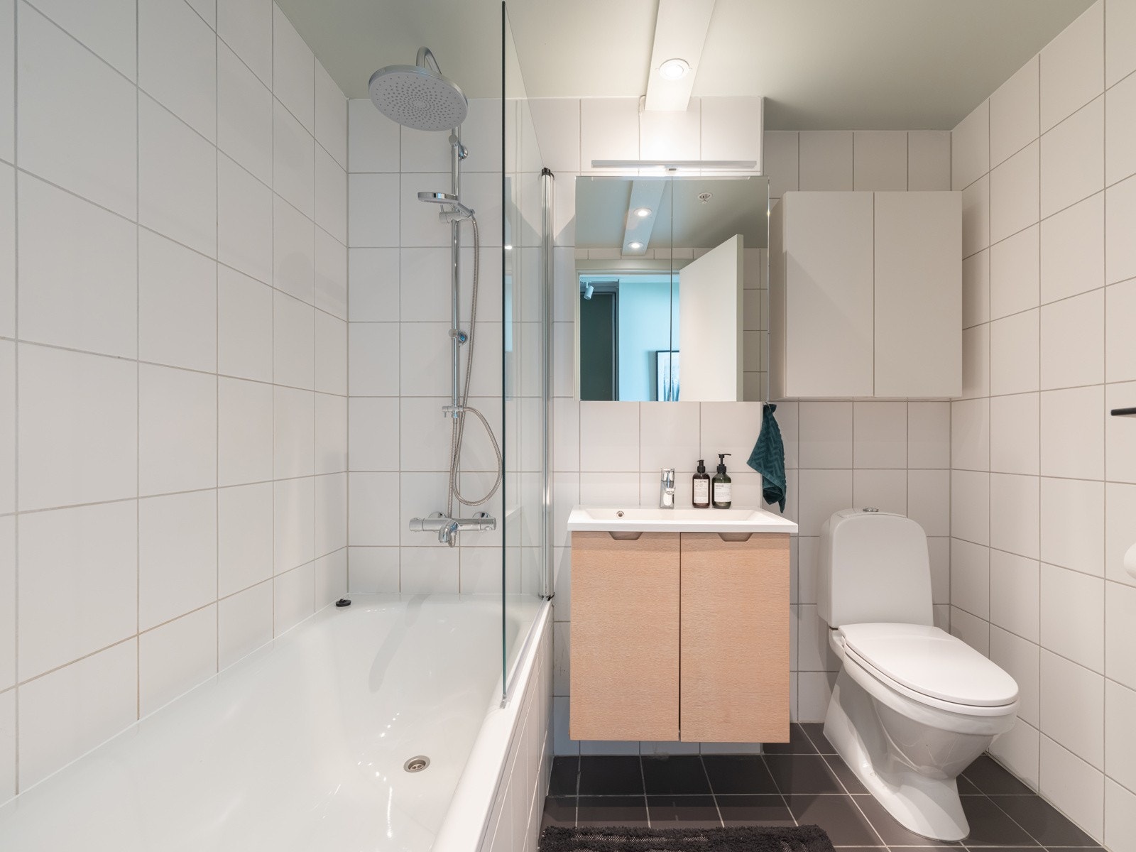 Pent og flislagt baderom med gulvvarme. Baderommet har vegghengt servantinnredning, heldekkende servant med ett-greps armatur, speilskap og stikkontakt på vegg, og skap på vegg. Galleribilde