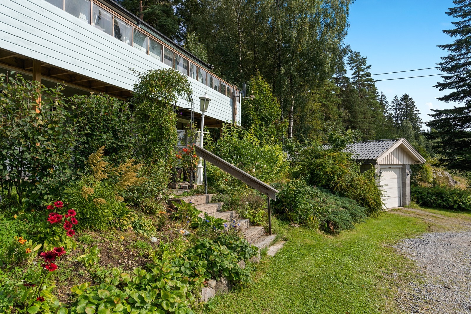 Hagen er full av blomster og busker som omkranser den sjarmerende trappen opp til huset. Galleribilde
