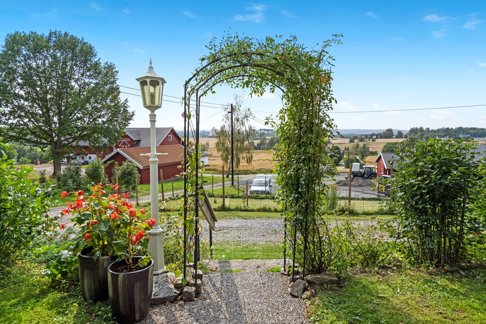 Hagebue dekket av klatreplanter som markeres inngangen til gårdsplassen, noe som gir et innbydende og naturlig preg. Galleribilde