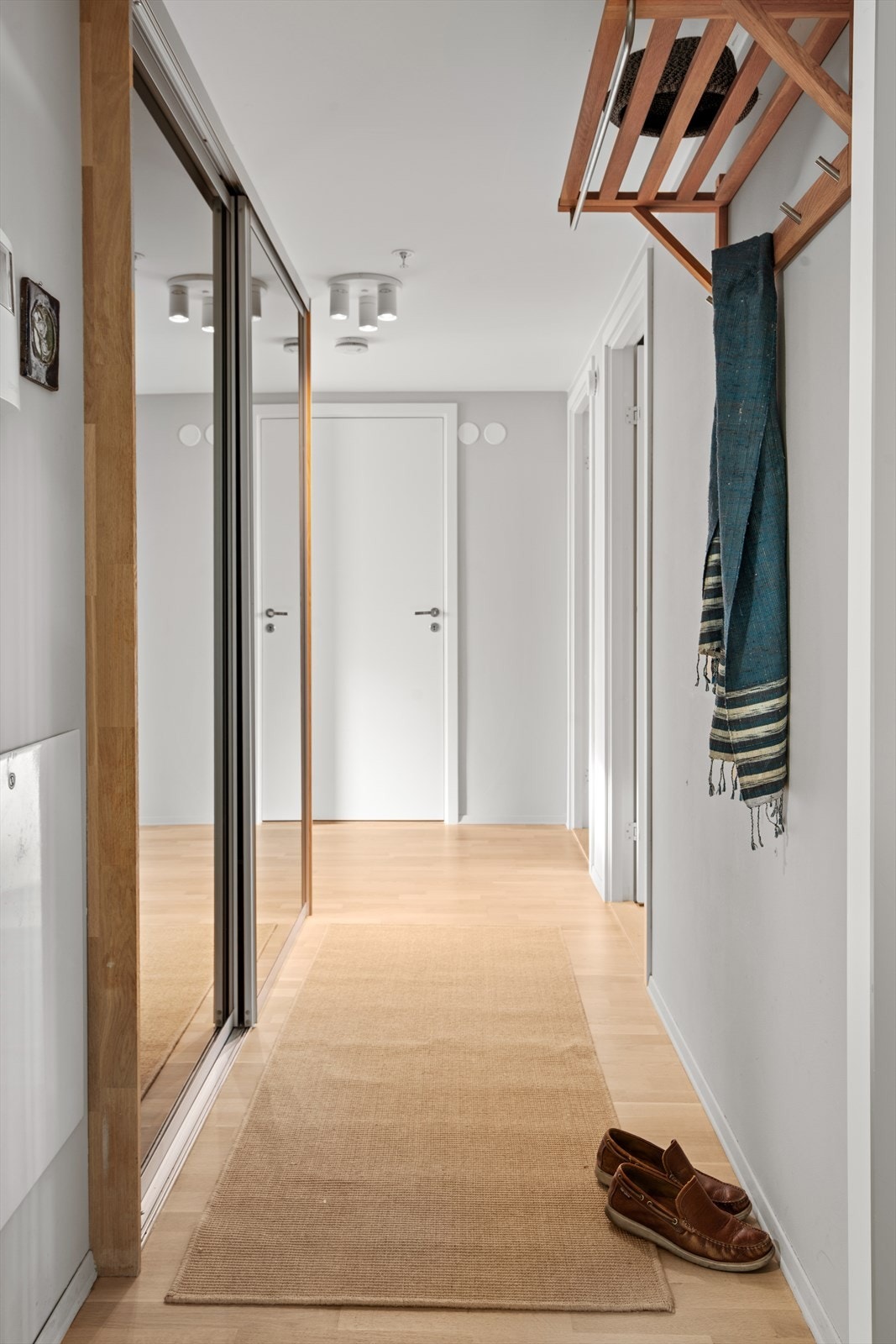 Man ankommer boligen i en innbydende entré med stor skyvedørsgarderobe med speilfronter som gir rikelig med oppbevaringsplass. Her er det også plass kommode eller annen praktisk oppbevaring. Galleribilde
