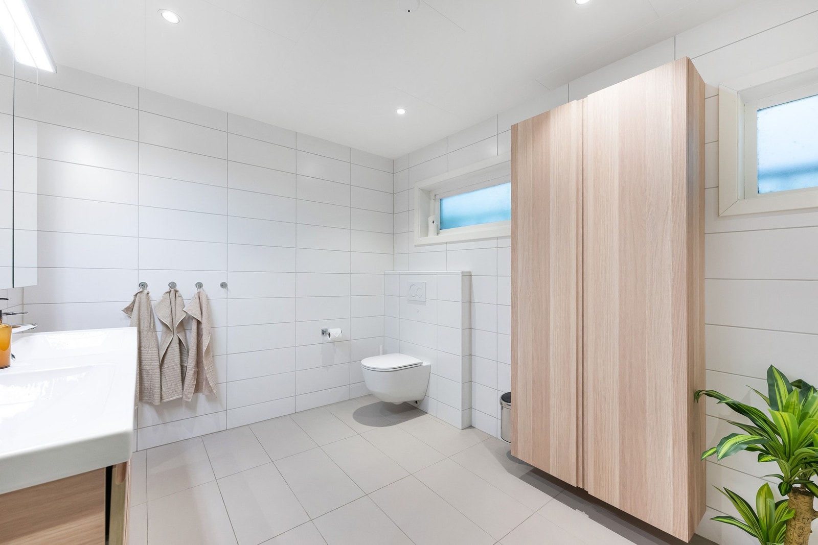 Badet er innredet med dusjvegg, to servanter, møbler og veggmontert wc. Galleribilde