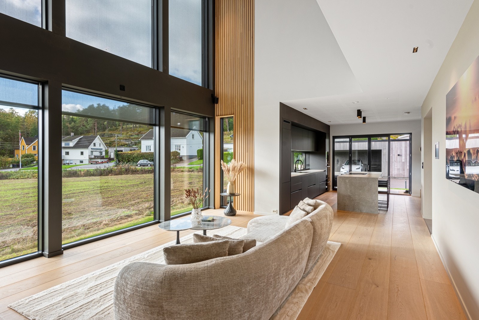 Stue og kjøkken er i åpen løsning med store vindusflater fra gulv til tak Galleribilde