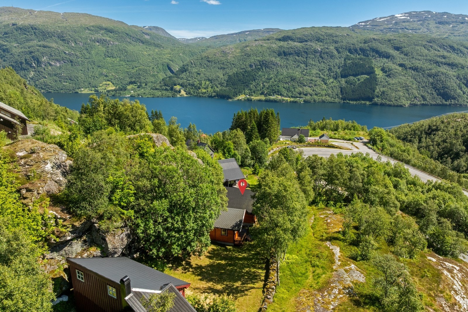 Parkering på felles parkeringsplass for hyttefeltet like nedenfor hytten i avkjørsel fra hovedvei. Gangsti fra parkering til hytten. Galleribilde
