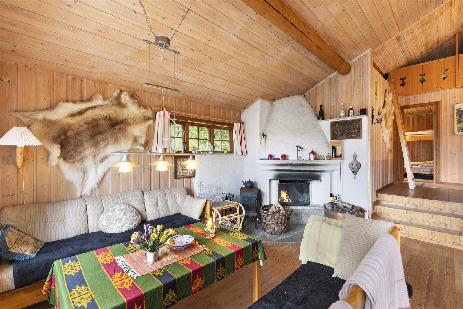 Stua gir en flott romfølelse med åpen himling og koselig peis. Galleribilde