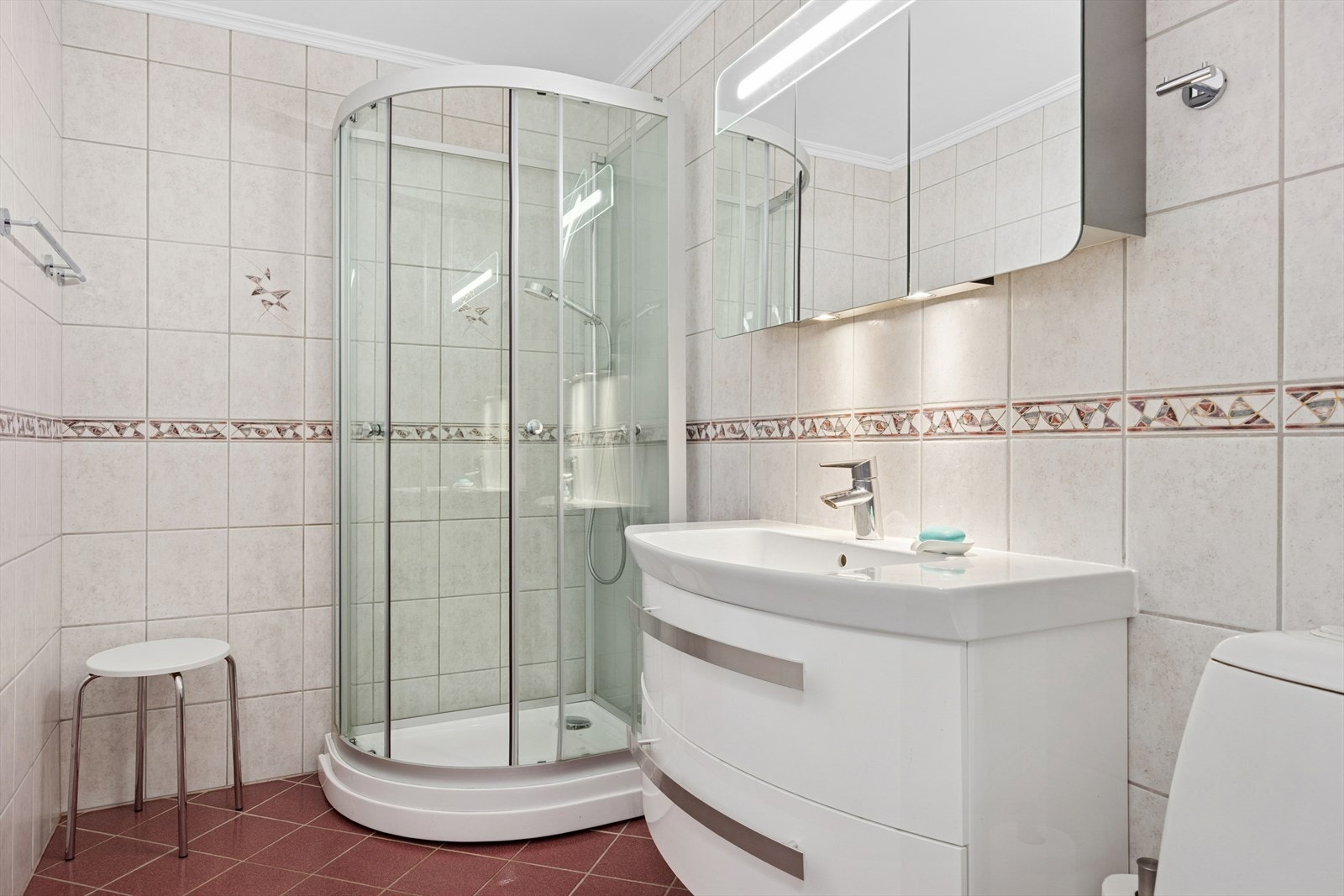 Badet er innredet med dusjkabinett, gulvmontert toalett og innredning med servant. Ventilasjonen skjer via ventil i vegg tilknyttet oppdriftskanal, med tilluft via spalte i dør. Galleribilde