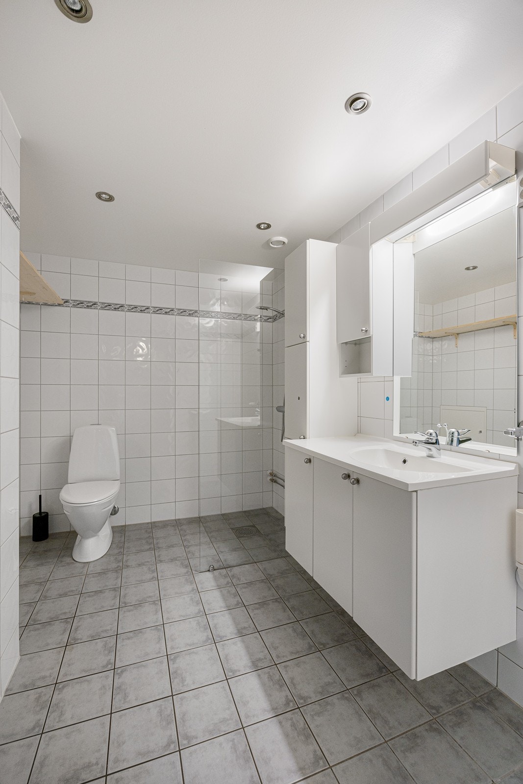 Badet er innredet med toalett, servant i baderomsinnredning, dusjhjørne og opplegg for vaskemaskin. Galleribilde