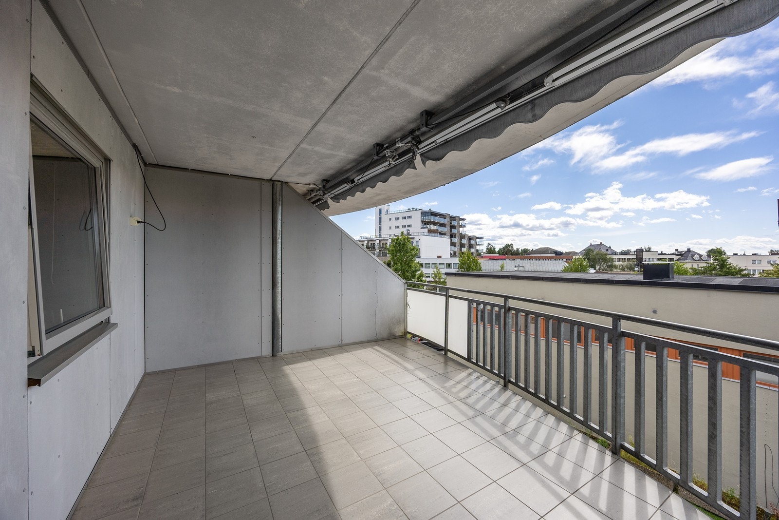 Det er adkomst fra stuen til en romslig overbygget balkong med terrassemarkise og flislagt dekke. Galleribilde