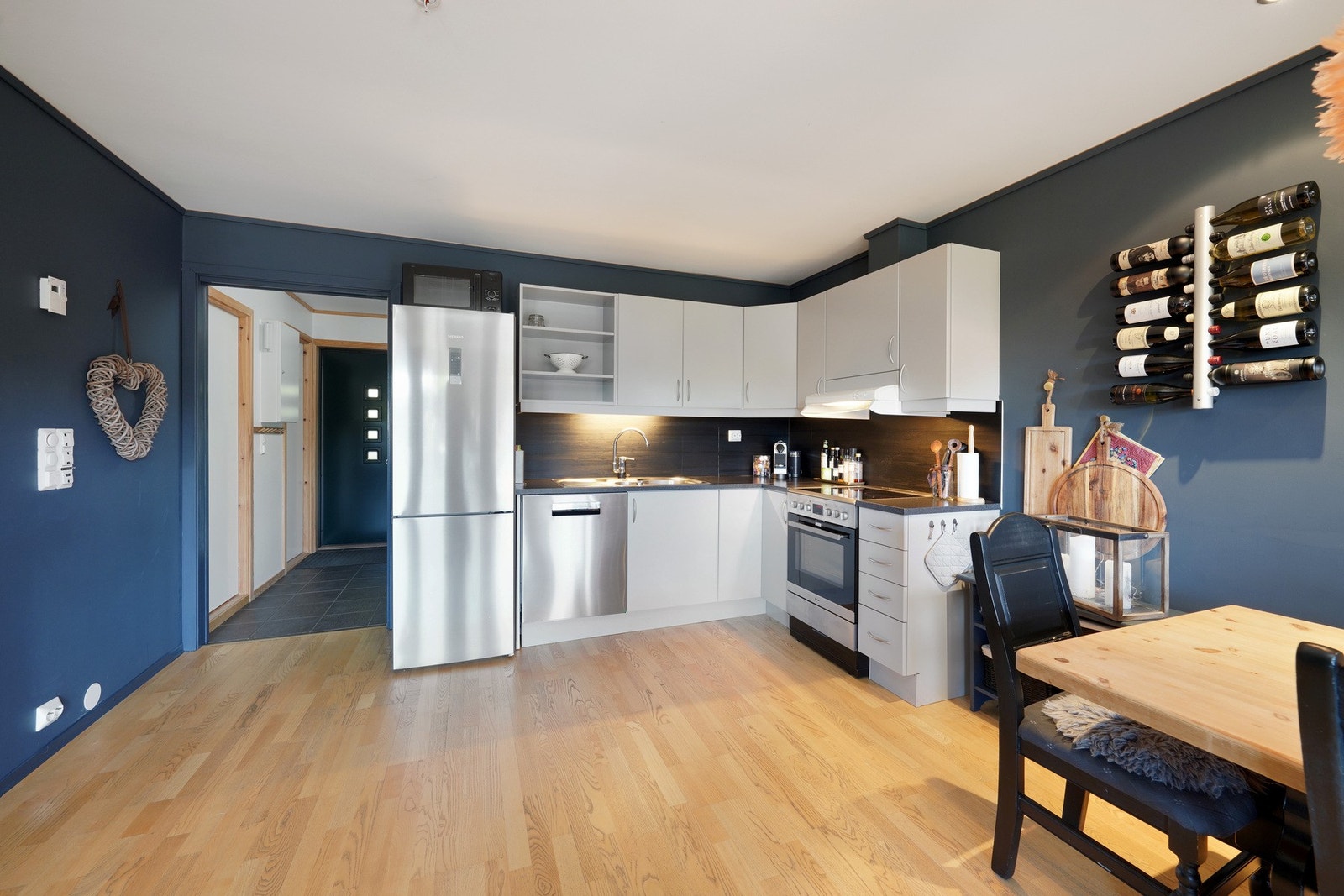 Kjøkkenet har fin benkeplate og gråtonet kjøkkeninnredning fra Strai med integrert oppvaskmaskin. Galleribilde