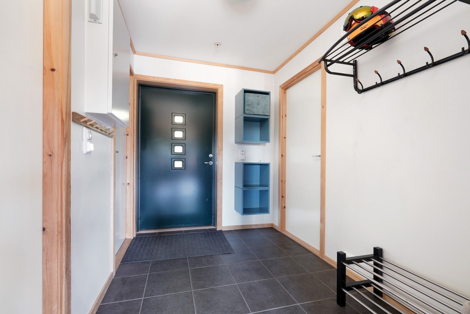 Entreen gir et godt førsteinntrykk av leiligheten, med fliser og varmekabler på gulvet, lyse overflater og smart oppheng for skihjelmer og ytterklær. Galleribilde