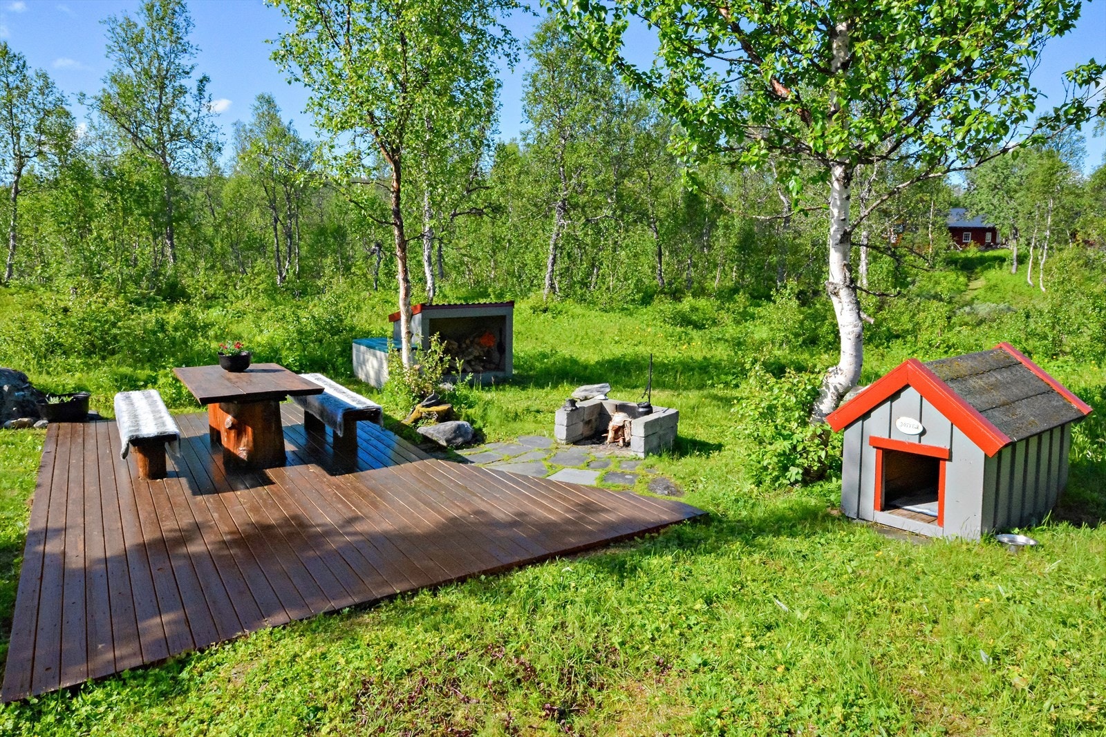 Eiendommen byr på et pent opparbeidet uteområde som innbyr til både rolige stunder og hyggelige sammenkomster. Her finner du en solid treplatting med bord og to klassiske trebenker - perfekt for morgenkaffen i solskinn eller lange sommerkvelder. Galleribilde