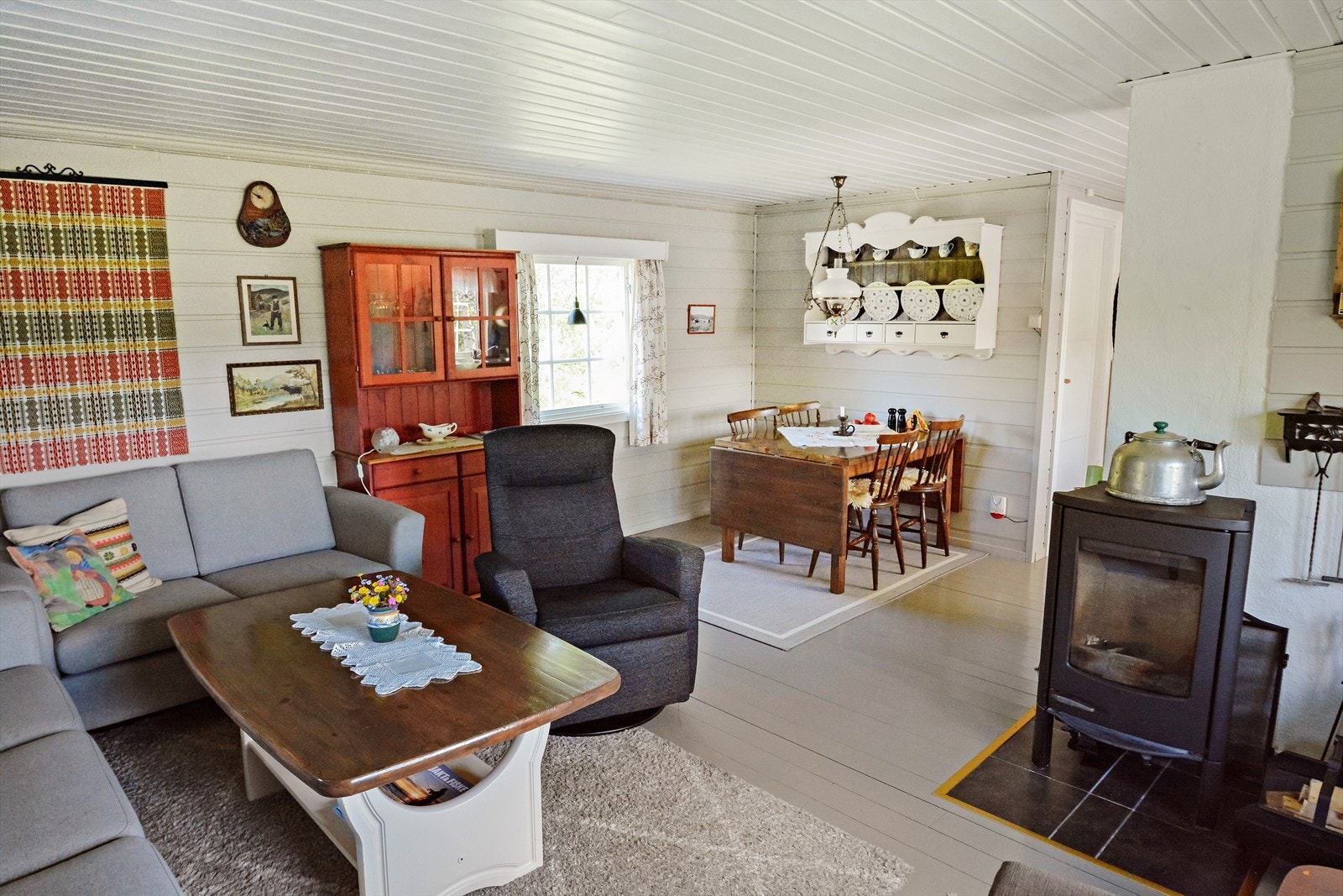 Åpen løsning mot mellom stuen og kjøkken skaper en sosial atmosfære, og vedovnen i stua sørger for både varme og stemning. Galleribilde