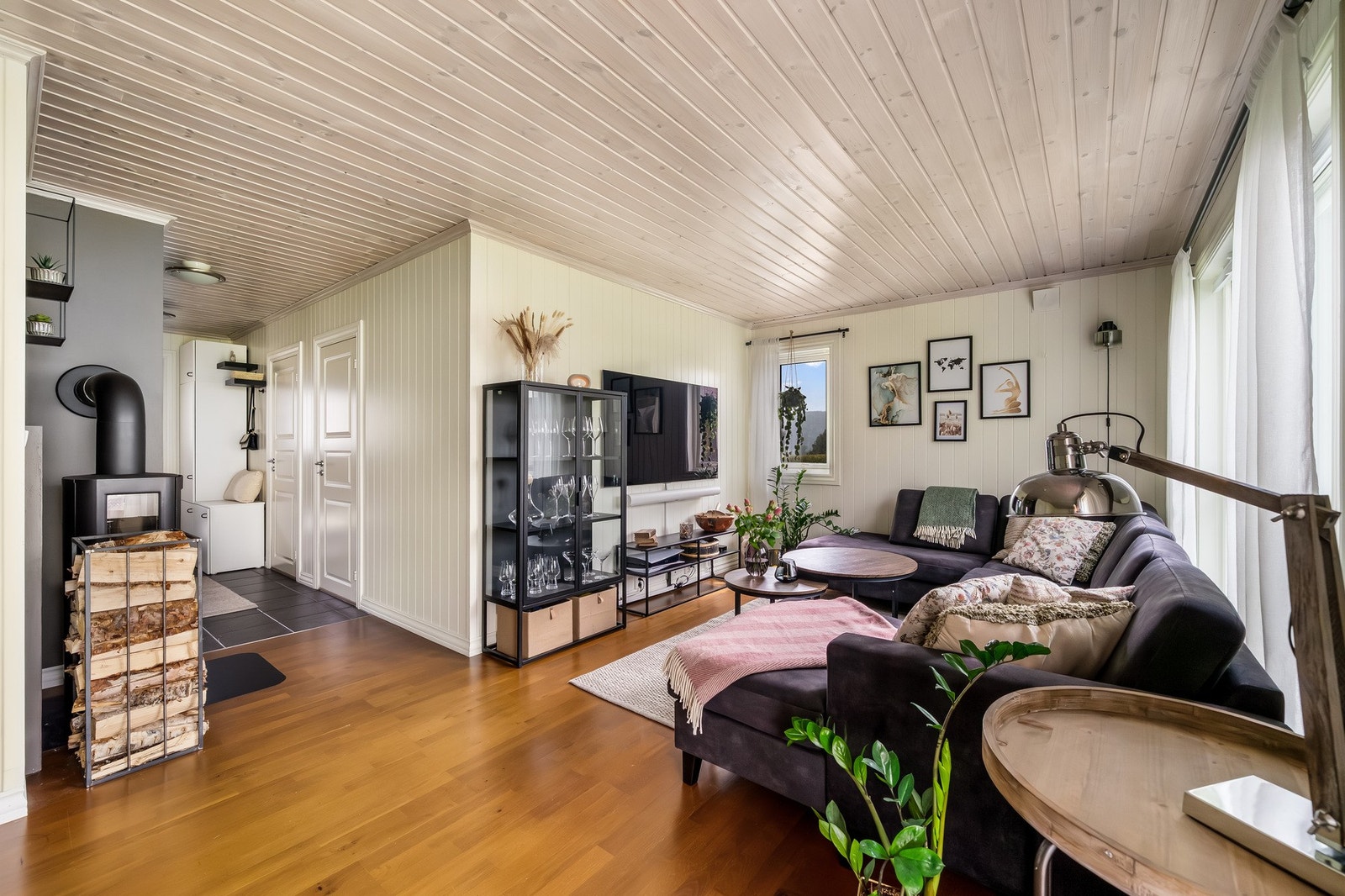 Åpen stue/kjøkkenløsning med lyse overflater og vedfyr. Galleribilde