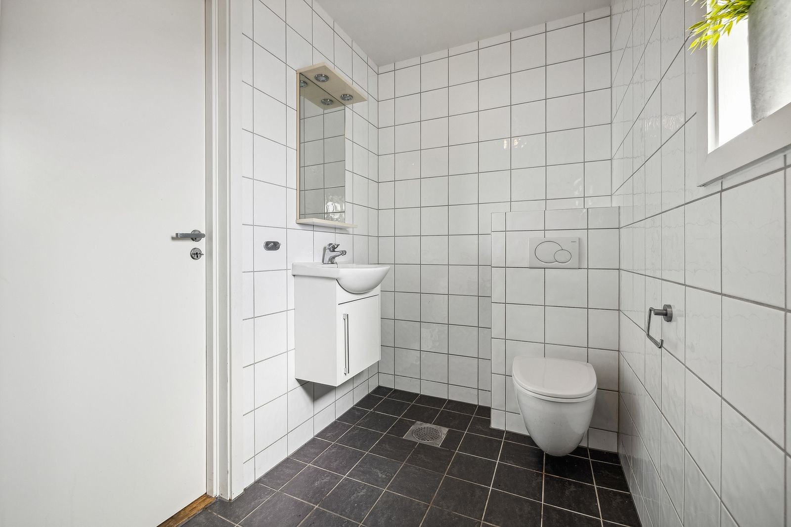 Gjestetoalett i 1. etasje som er helfliset med varmekabler i gulv. Her er det innredet med veggehengt toalett
og vask i seksjon. Galleribilde