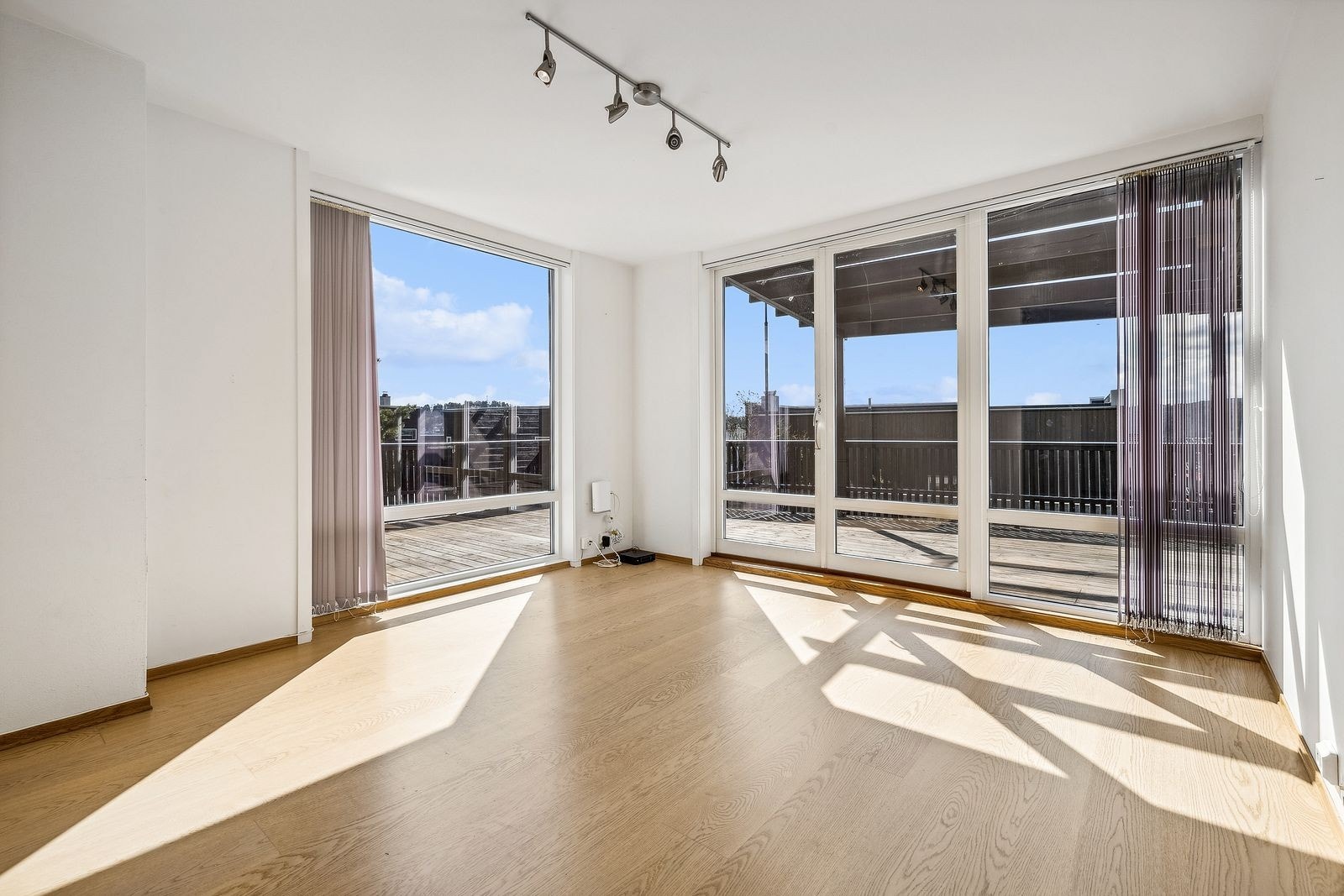 Lys stue i underetasjen med flere store vindusflater. Galleribilde