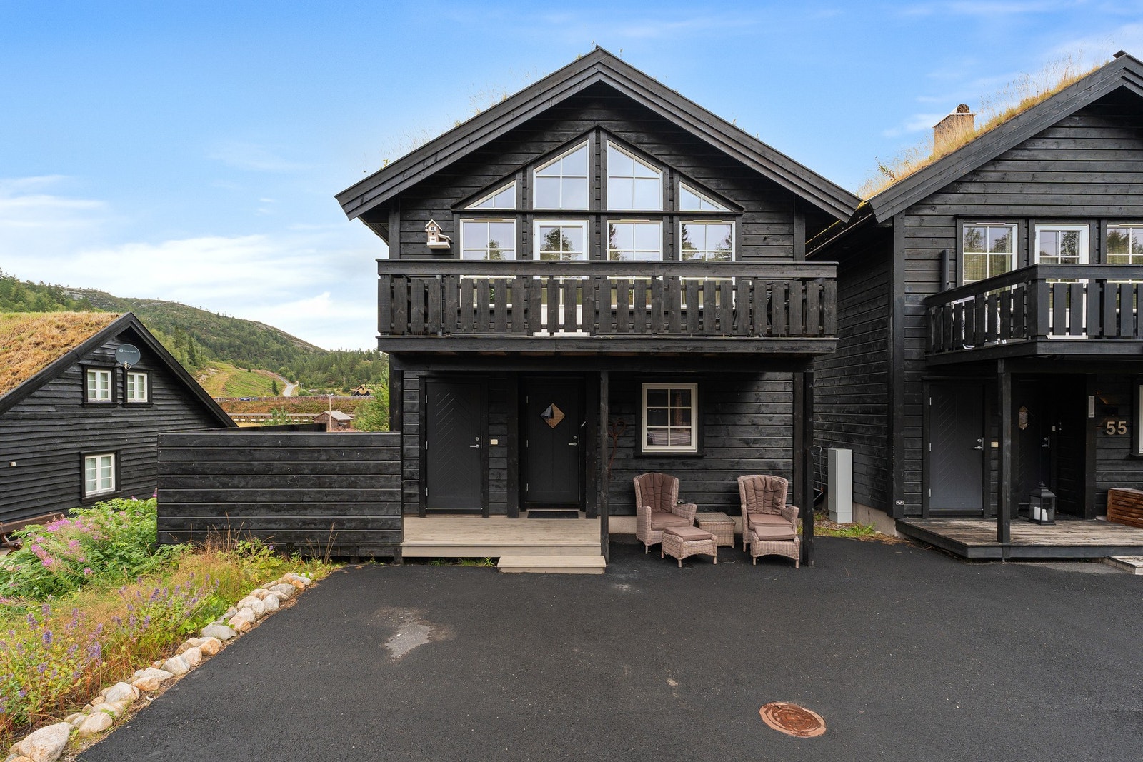 Moderne, svartmalt hytte med balkong og asfaltert gårdsplass. Bod ved inngangsparti hvor man kan plassere ski utstyr og div. Galleribilde