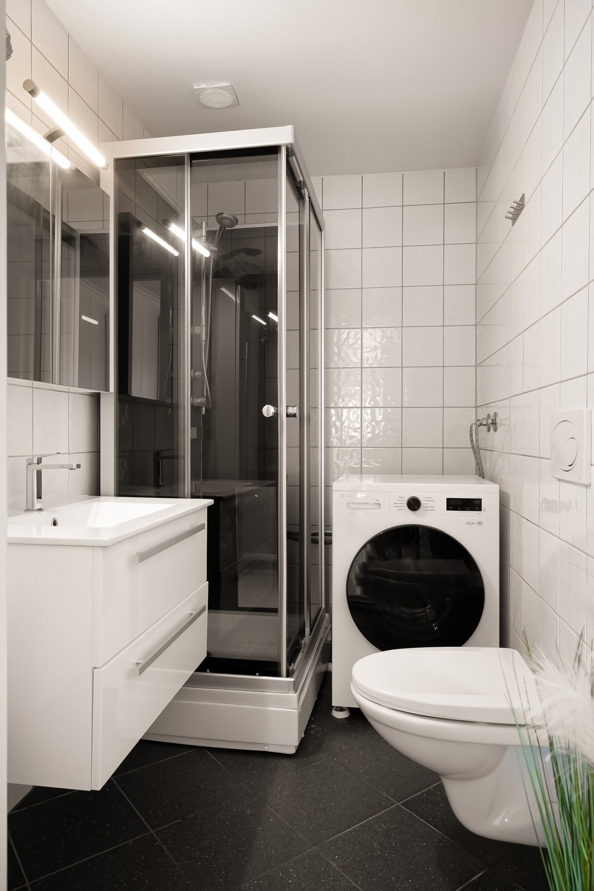 Flislagt bad med vegghengt toalett, servant og dusjkabinett. Galleribilde