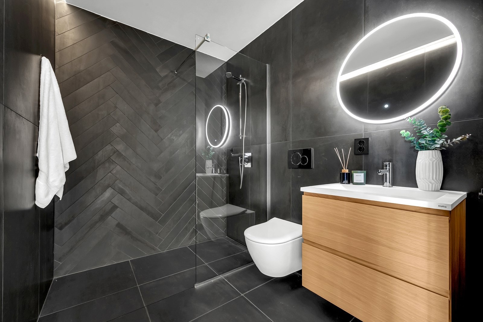 Badet er innredet med romslig dusjhjørne, toalett, servant med oppbevaring og varme i gulv Galleribilde