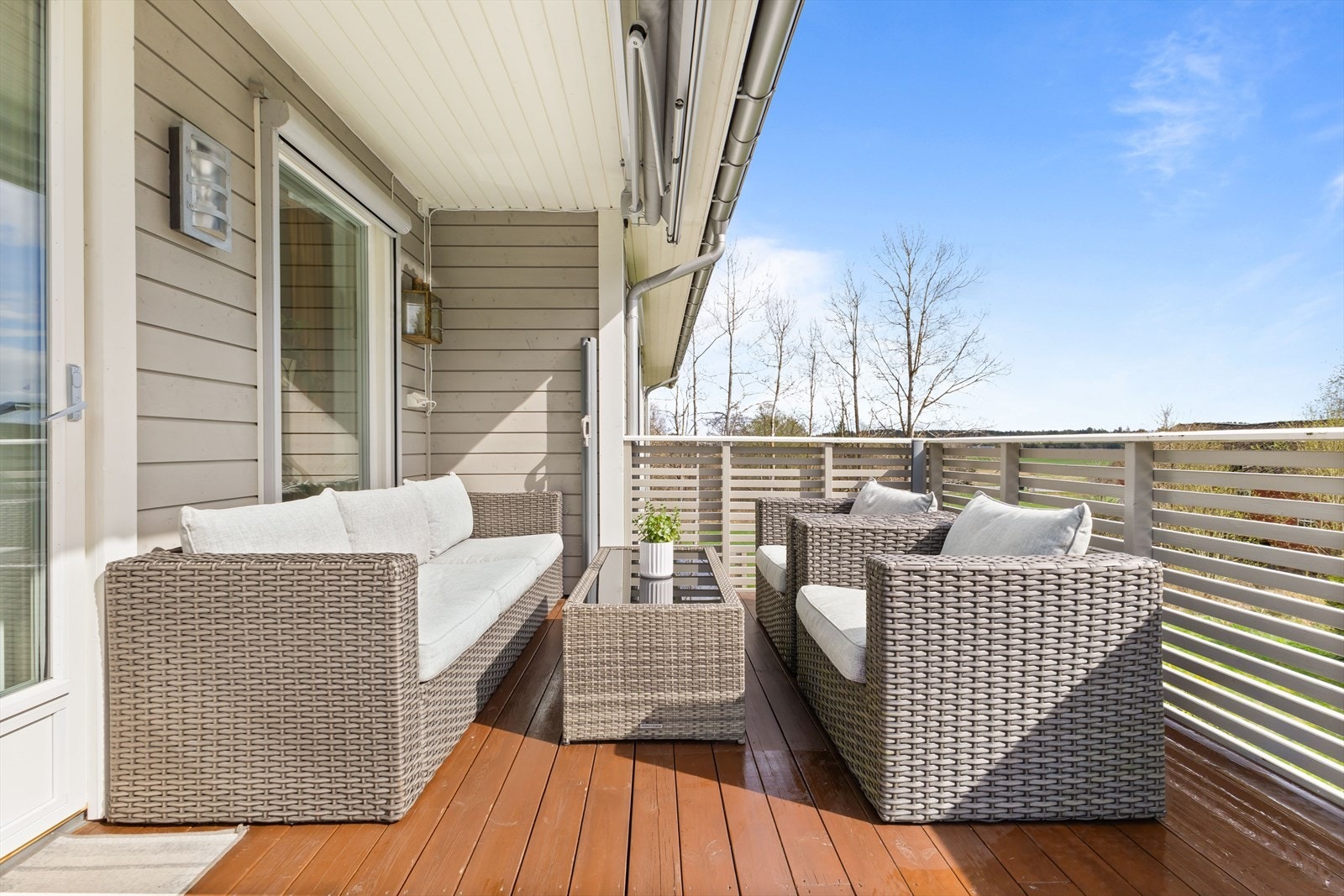 Balkongen har beiset terrassebord. Rekkverk med liggende spiler. Markise. Galleribilde