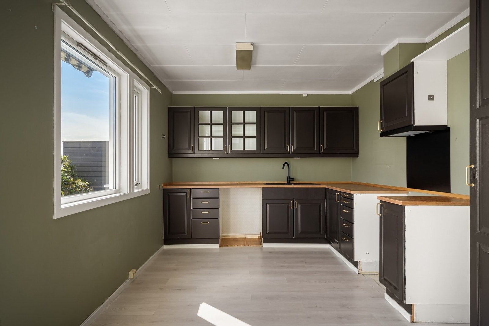 Mørk, profilert kjøkkeninnredning med plass til hvitevarer Galleribilde