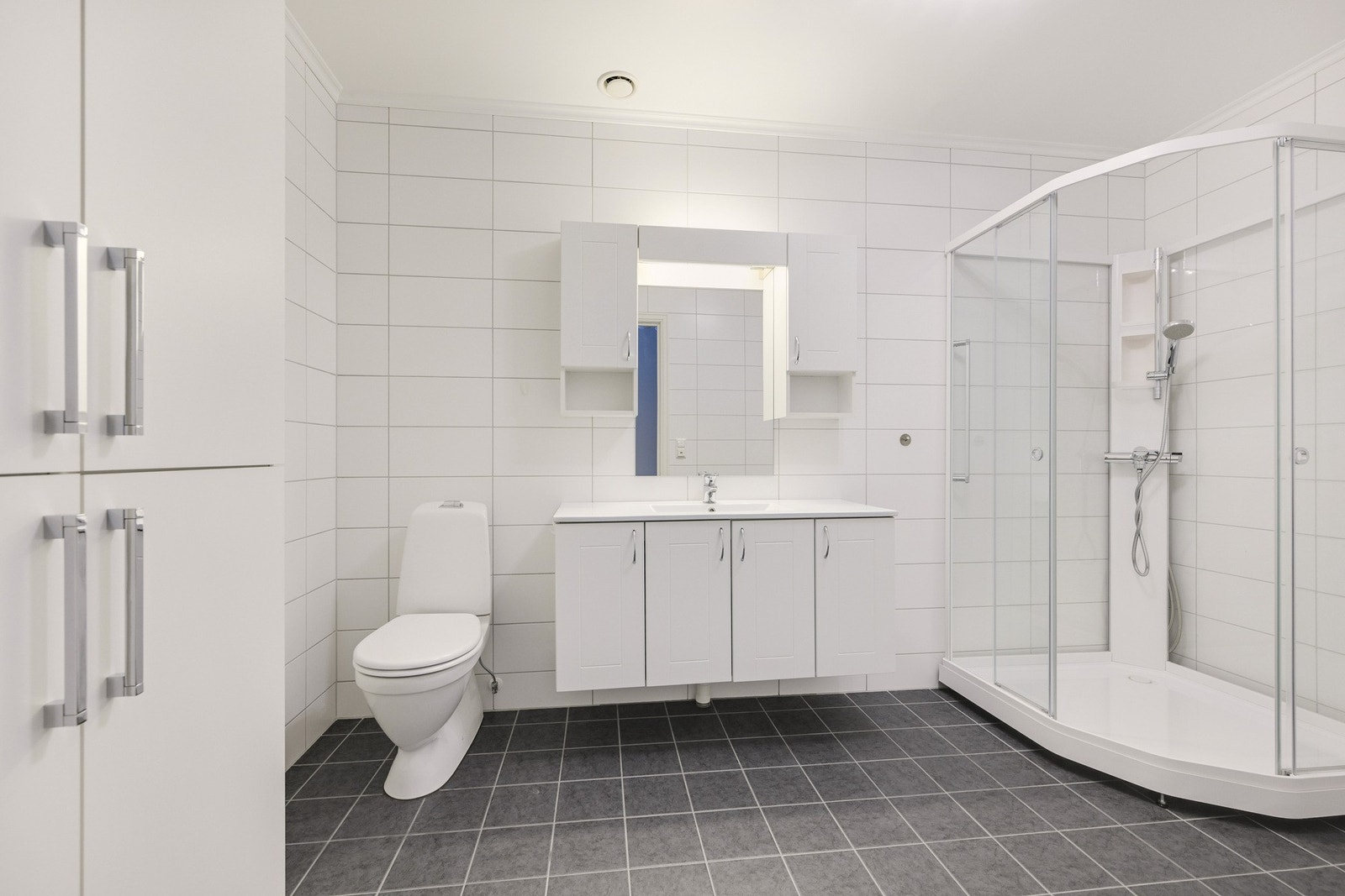 Baderommet/vaskerommet er svært romslig. Her har man fått installert et dusjkabinett, en stor og hvit innredning med over -og underskap med speil og belysning. Galleribilde