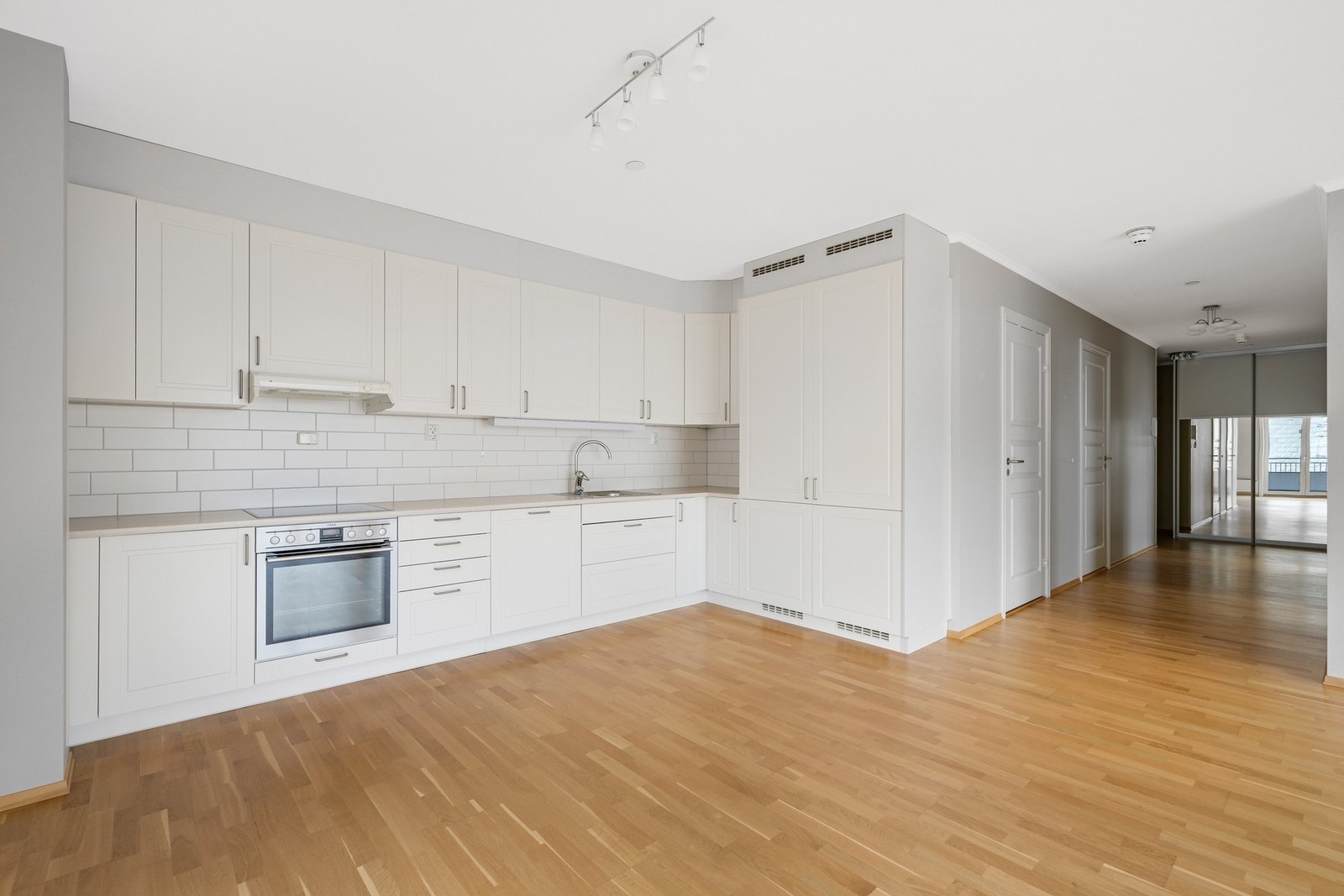 Velkommen inn. Stuen og kjøkkenet er i ett med åpen og luftig planløsning. Her er det romslig kjøkkeninnredning med hvite fronter og integrerte hvitevarer. Galleribilde