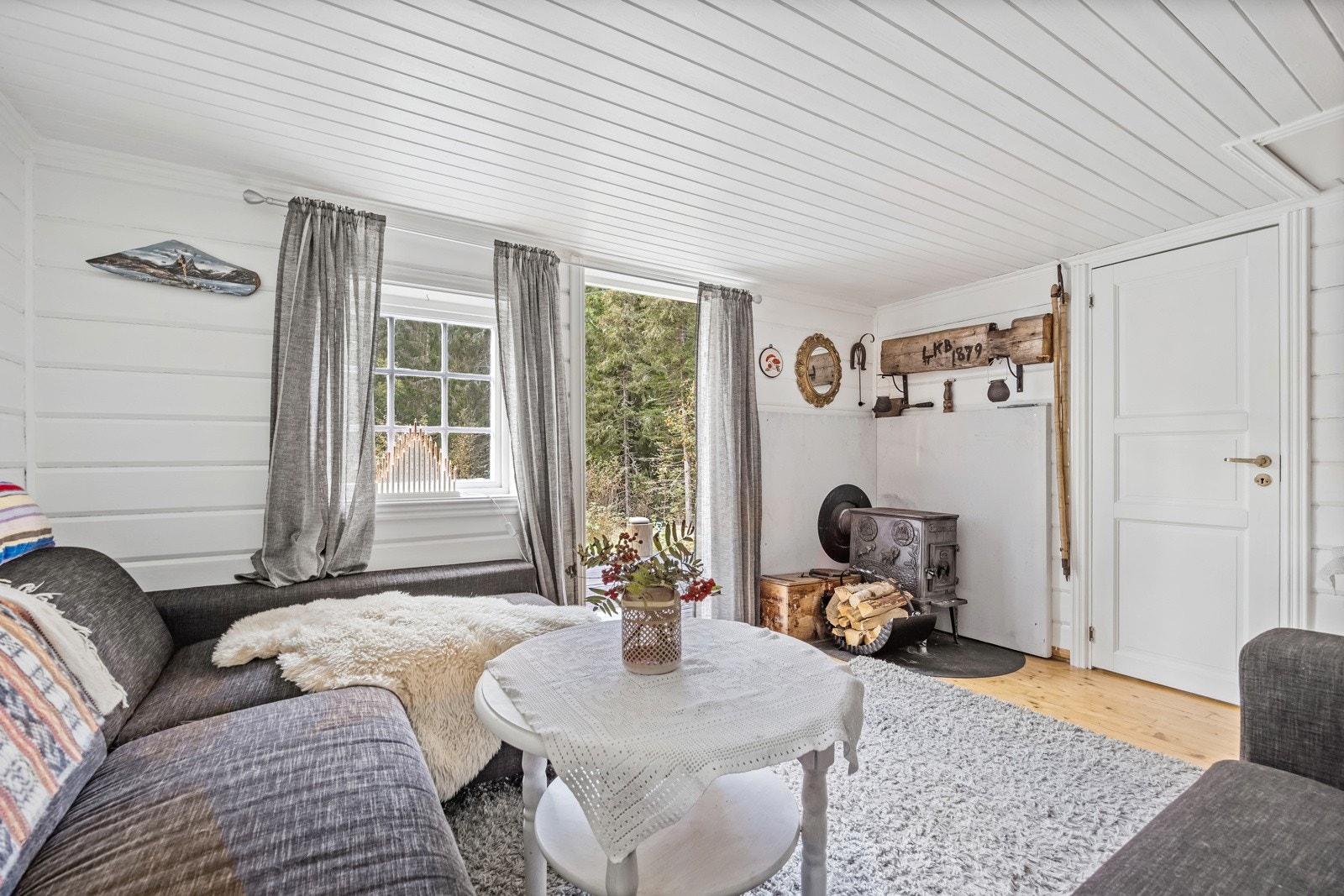 Hjemmekoselig atmosfære med peisovn, myke tekstiler og store vinduer som slipper inn naturlig lys fra de naturskjønne omgivelsene. Galleribilde