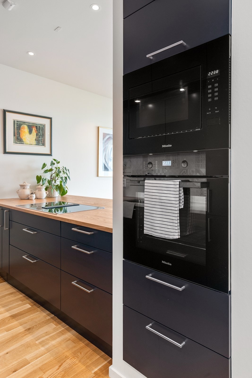 Integrerte hvitevarer som: induksjonstopp med integrert ventilator med kullfilter, stekeovn, mikrobølgeovn, oppvaskmaskin og kjøle- og fryseskap Galleribilde