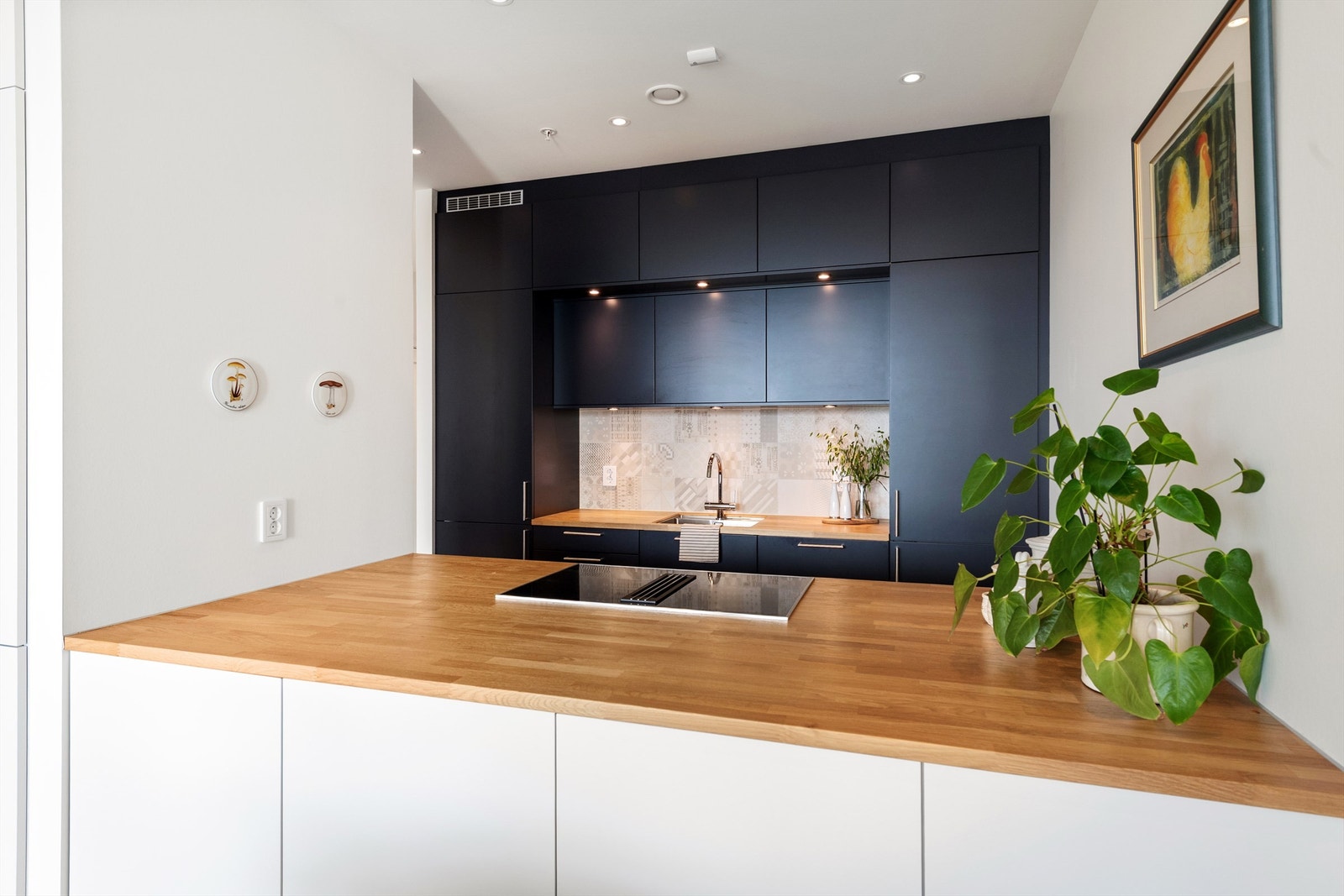 Kjøkkenet har takhøye skap med gode oppbevaringsmuligheter samt praktisk kjøkkenøy mot stuedel Galleribilde