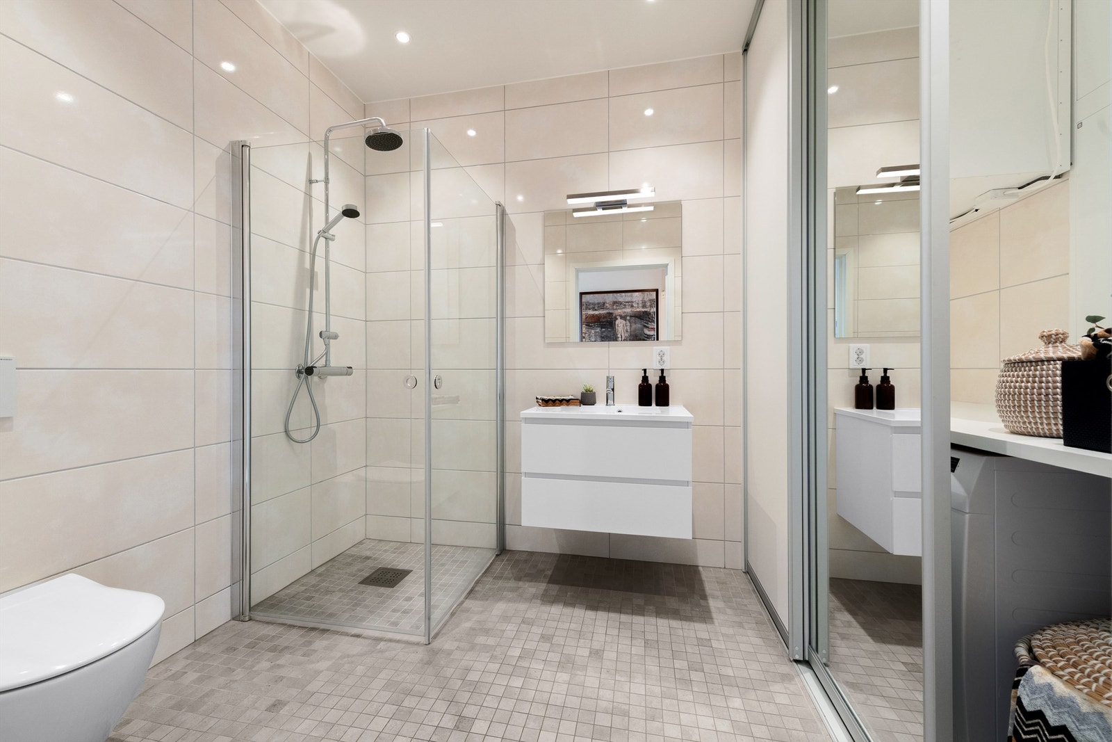 Bad/vaskerom med innredning, dusjhjørne, vegghengt toalett og vaskeromsnisje plassert bad skyvedørsfronter Galleribilde