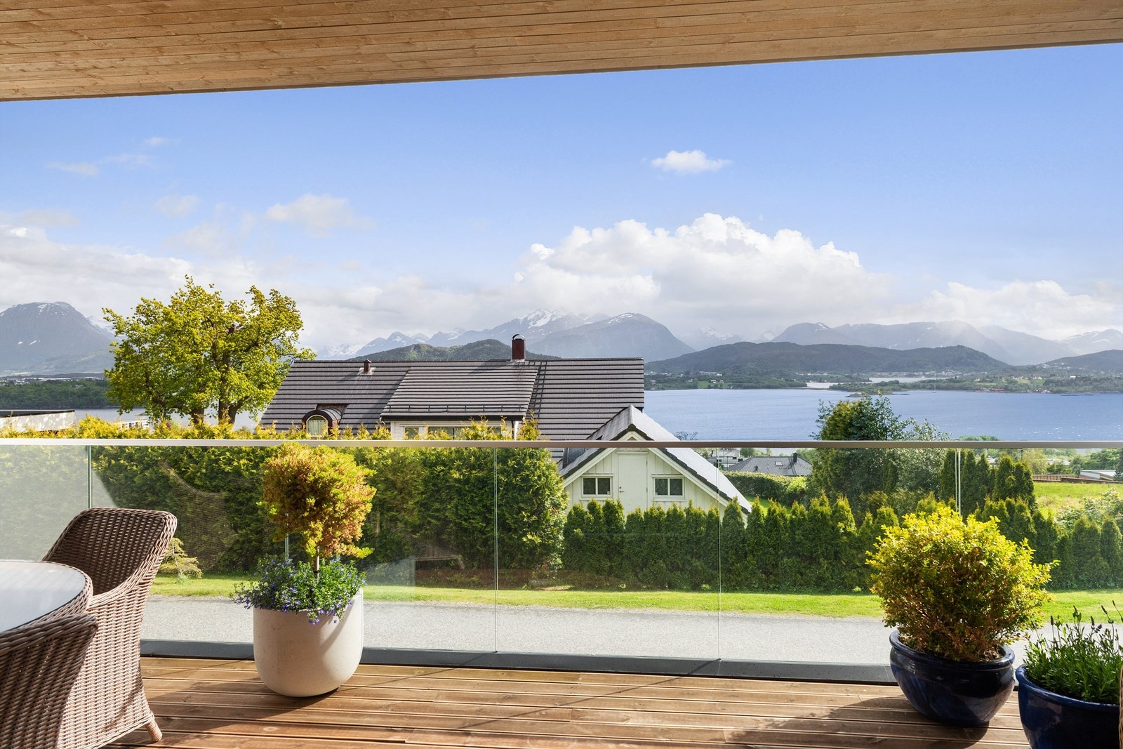 Stor skjermet terrasse mot syd med glassrekkverk. Flott utsikt mot fjorden og Sunnmørsfjella Galleribilde