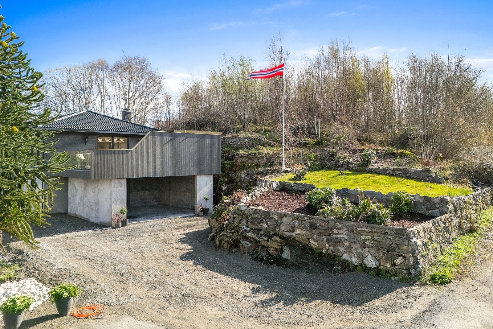 Tomten er skrånende og har gruset adkomst og tun. Galleribilde