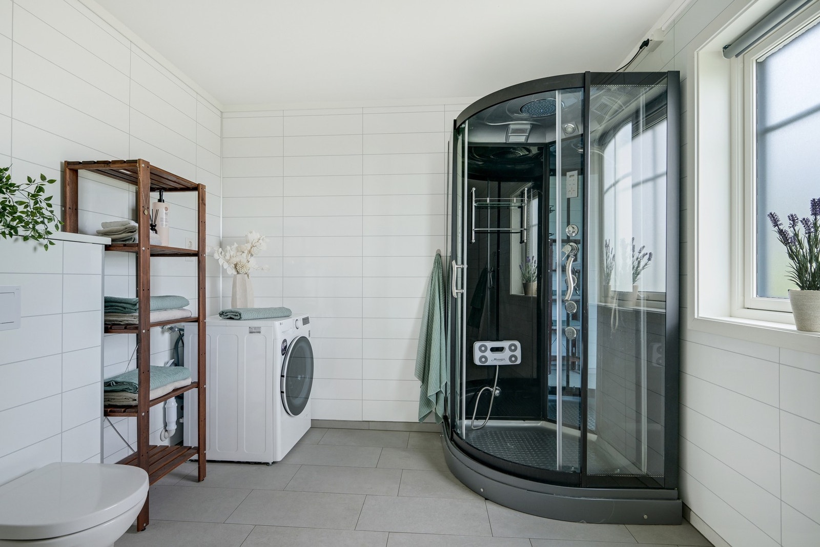 Boligen inneholder 4 baderom. Dette er hovedbadet i 1. etasje med store fliser på gulvet og laminerte baderomsplater på veggene. Badet fremstår som lyst og romslig. Galleribilde